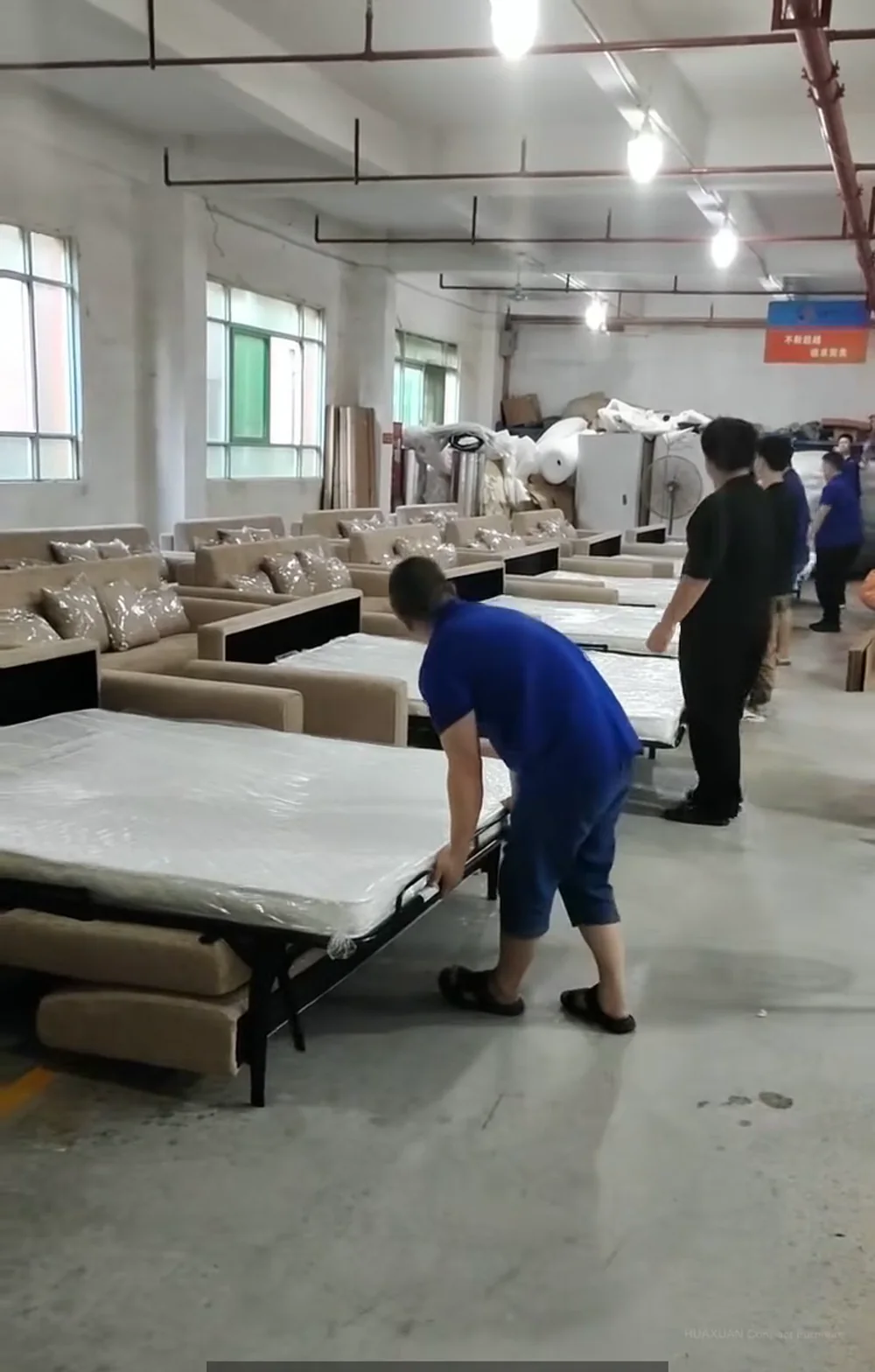 Worker checking sofa bed folding function before packing