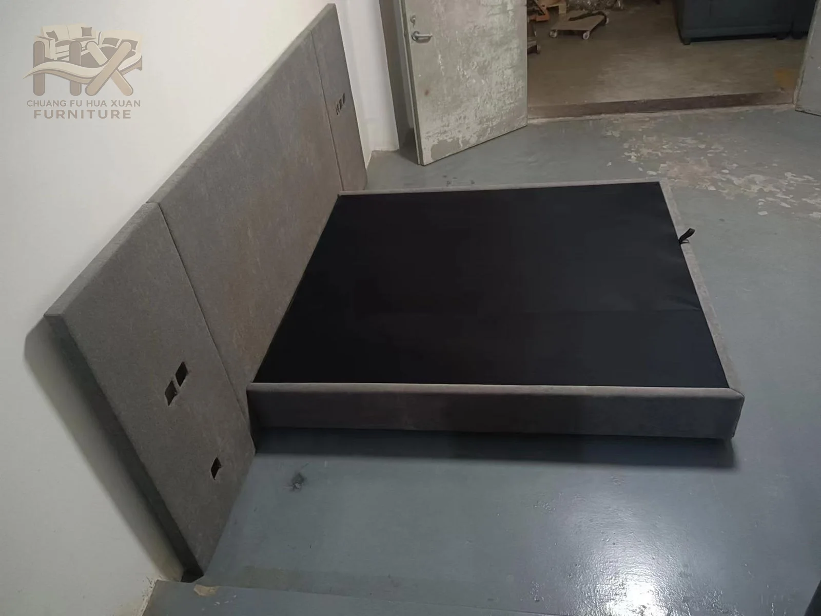 A deep grey headboard is divided into large vertical panels above a dark low platform.