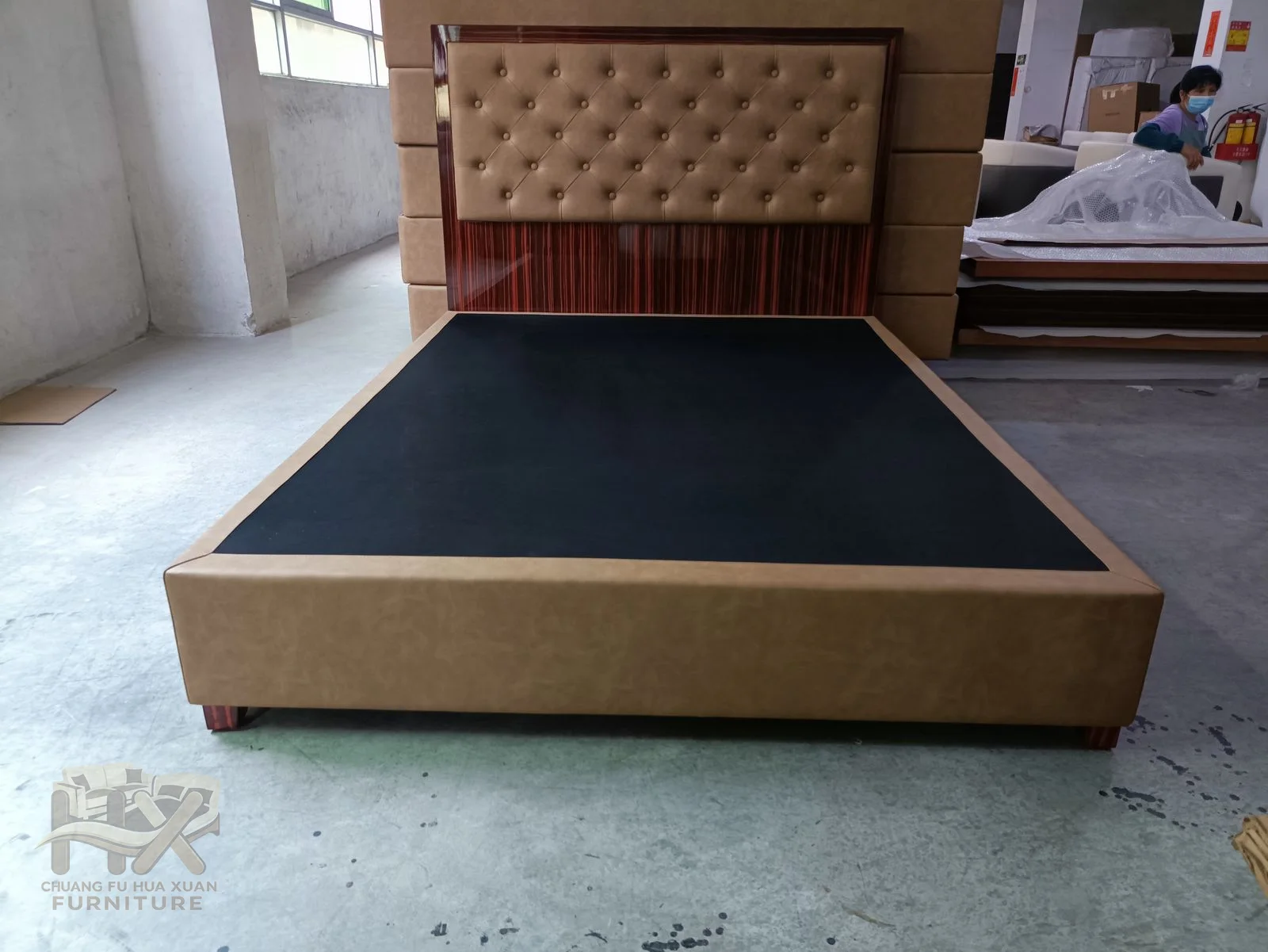 A tan upholstered headboard uses regular buttons above a matching low platform frame.