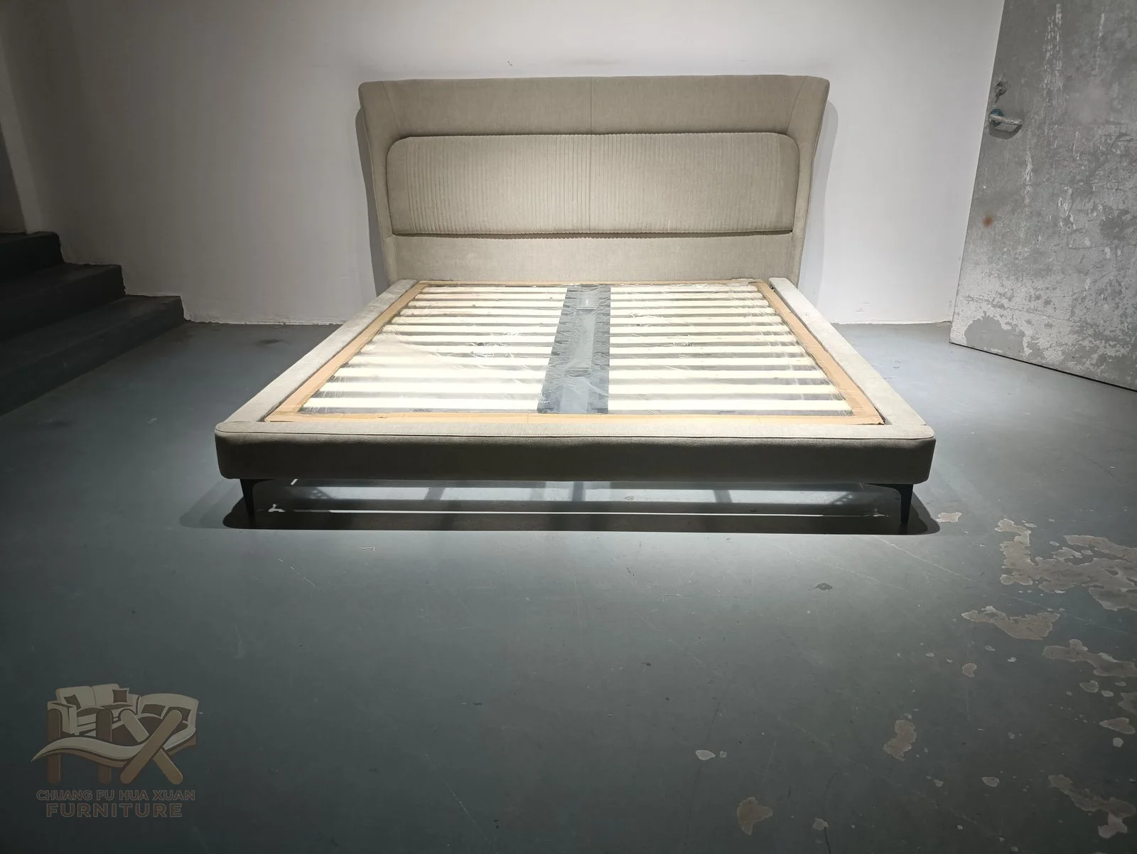 A low grey bed frame sits below a padded headboard marked by broad horizontal divisions.