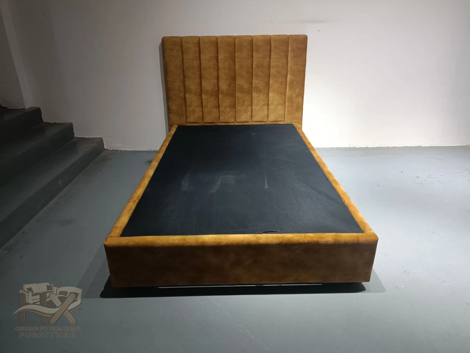 A warm-toned headboard sits behind a dark low bed surround with a visible slatted support.
