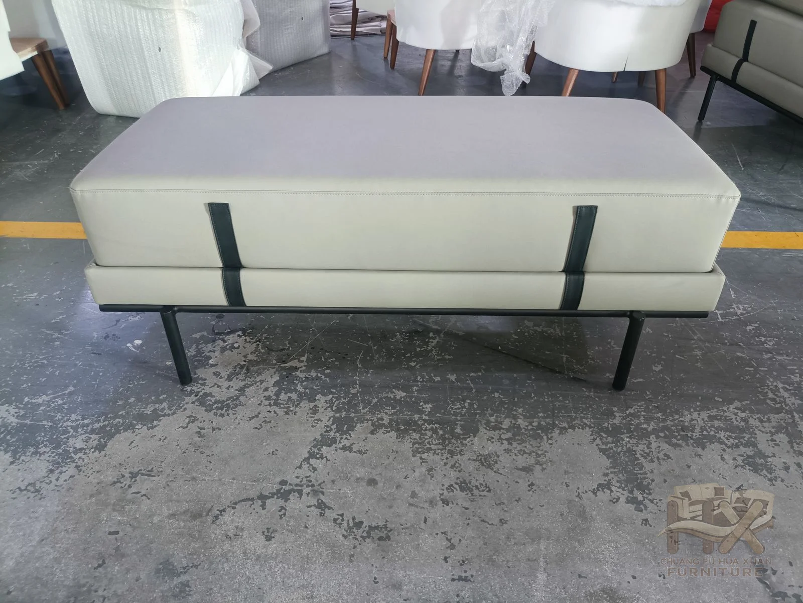 A long white upholstered bench rests on exposed thin dark legs.