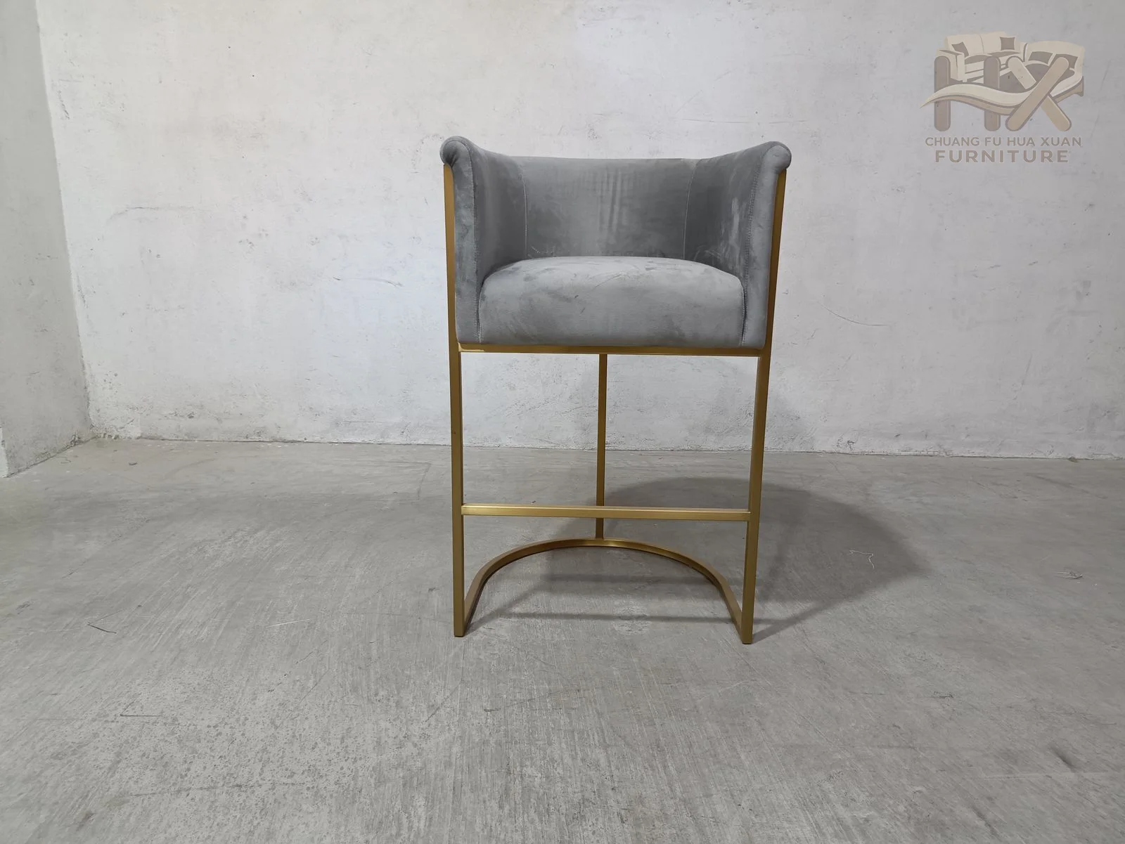 A small upholstered shell sits on a thin brass-tone frame that curves into a footrest beneath the seat.