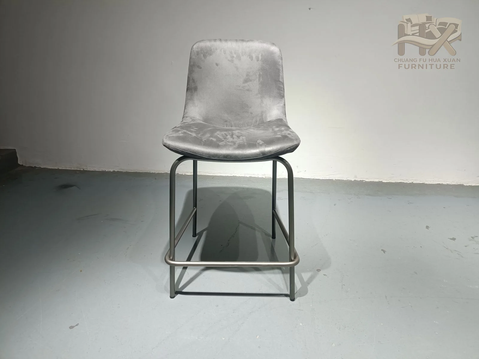A pale upholstered tall back and seat stand over a slim metal-look high base with a low crossbar.
