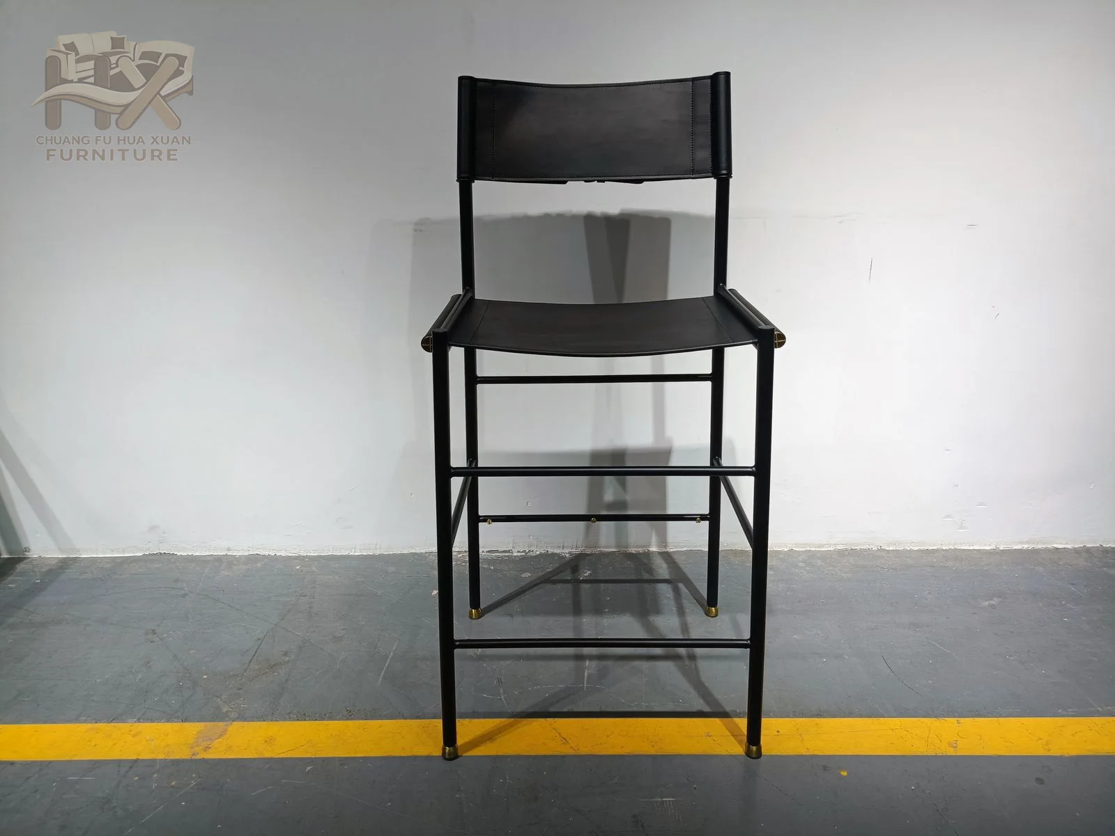 A black bar-height chair combines a padded seat and back with slim high legs.
