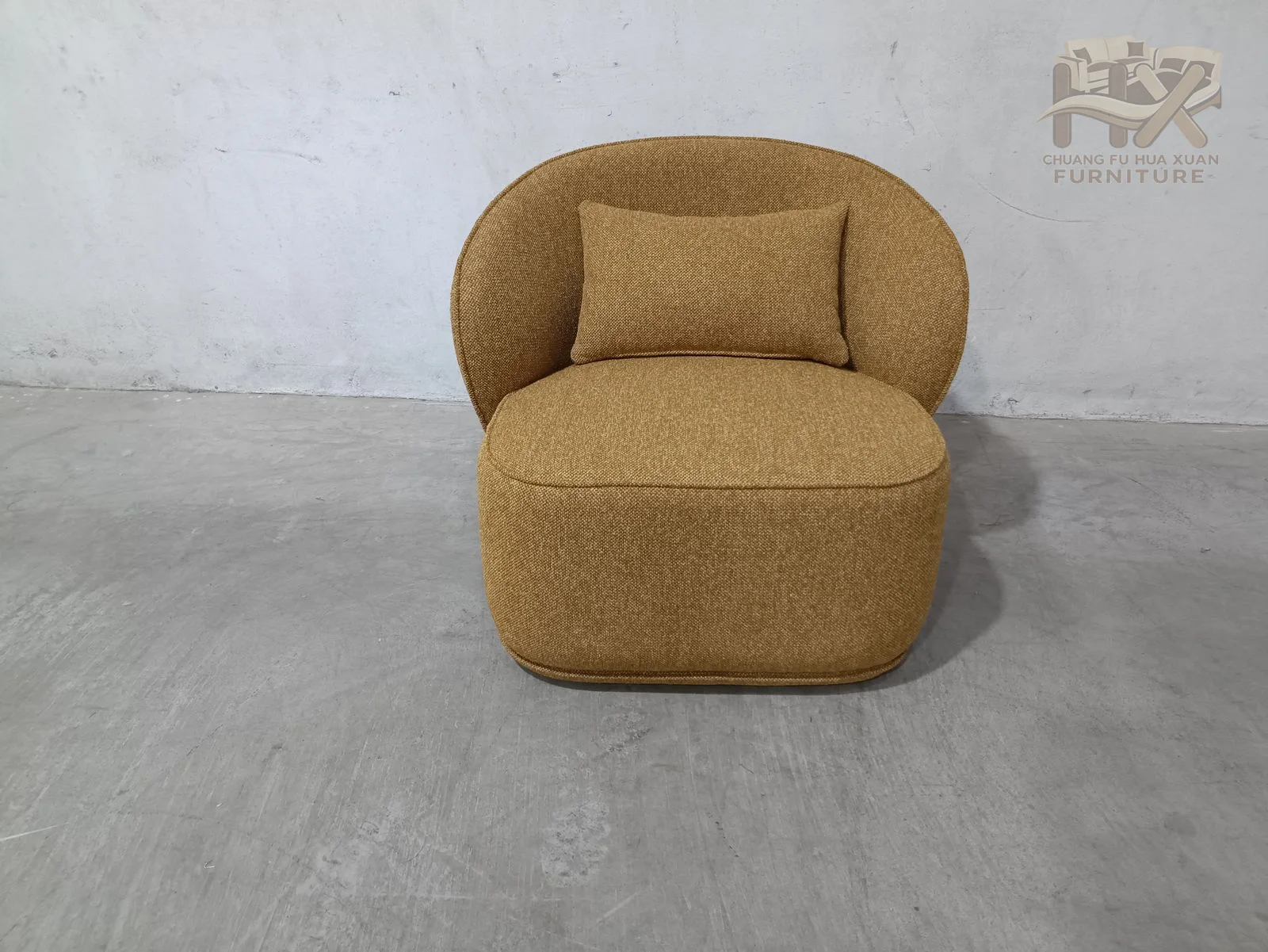 A plump rounded back encloses a low seat and two inset arms, producing a compact mustard chair with a nearly continuous upholstered surface.
