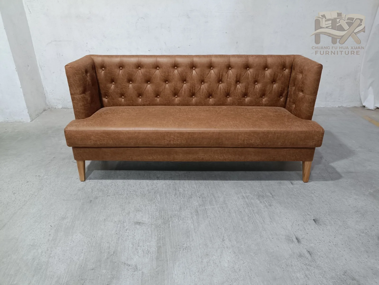 The tall upholstered back carries regular buttoning above a slim seat, with narrow arms and exposed tapered legs at each end.