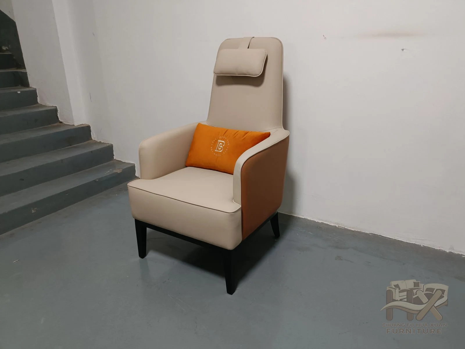 An upright headrest tops the tall lounge chair, while warm brown side panels frame the pale upholstery and a small matching footstool.