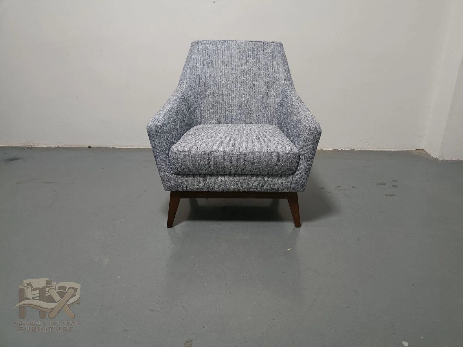 The grey chair combines a high narrow back, short flared arms and a low, substantial seat cushion.