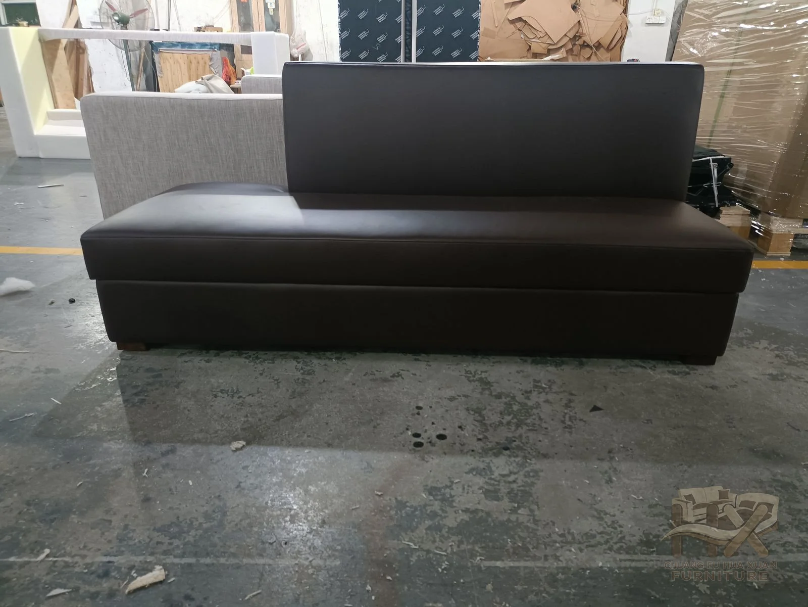 A high, nearly vertical back rises from a simple bench seat, with deep brown upholstery and no exposed legs.