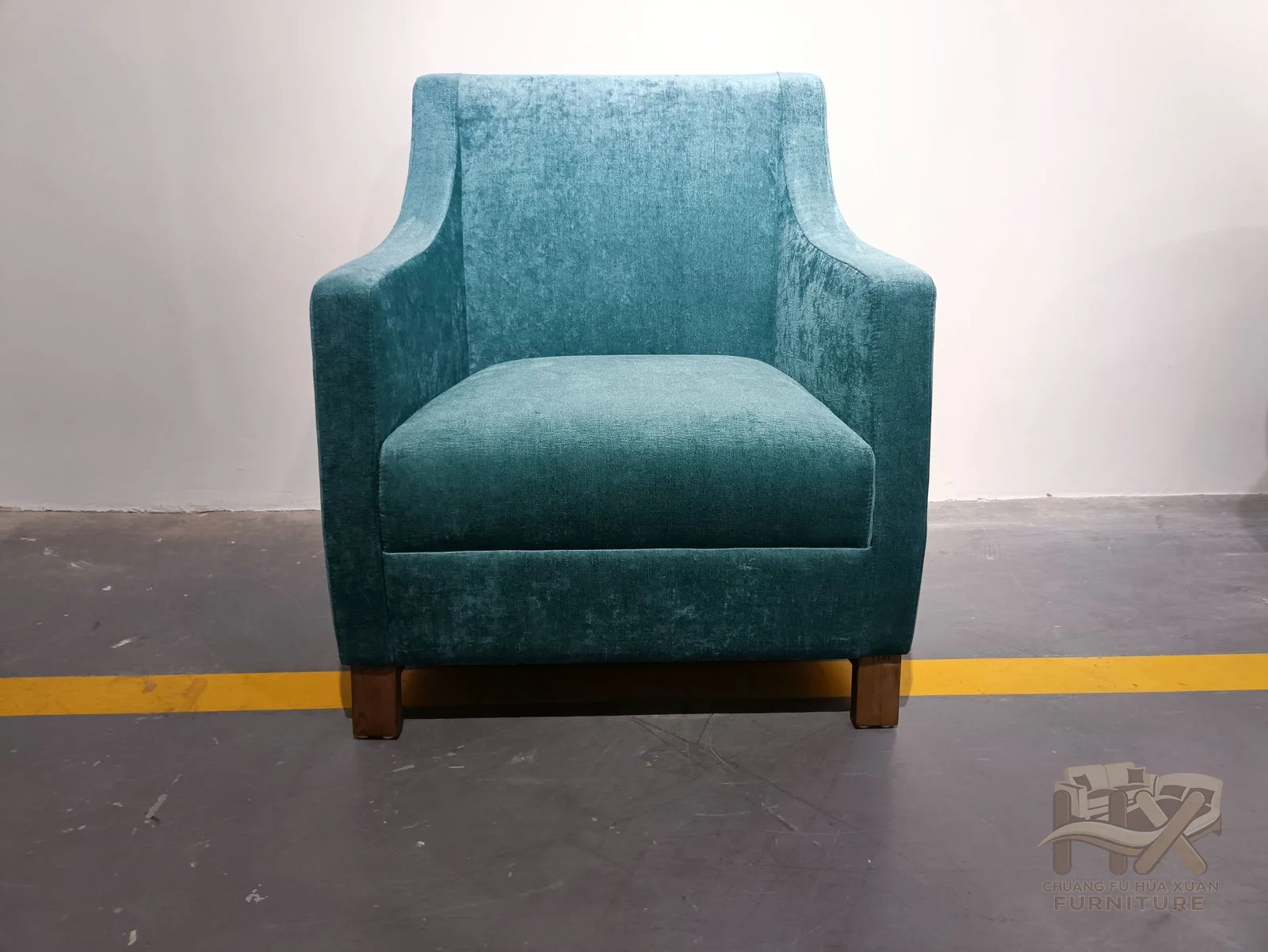 A tall teal back turns outward at the shoulders above straight upholstered arms and a compact seat.