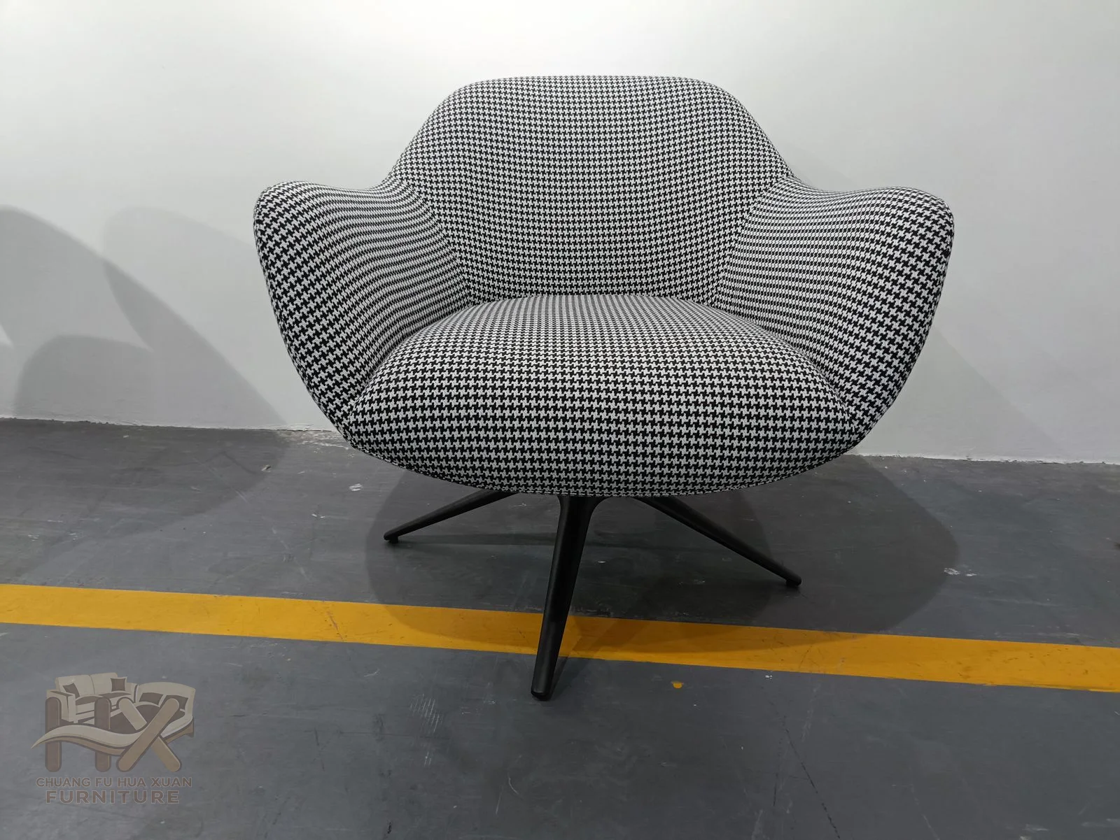 The petal-shaped grey seat has a pinched waist and broad curved arms above a dark cross-shaped swivel base.