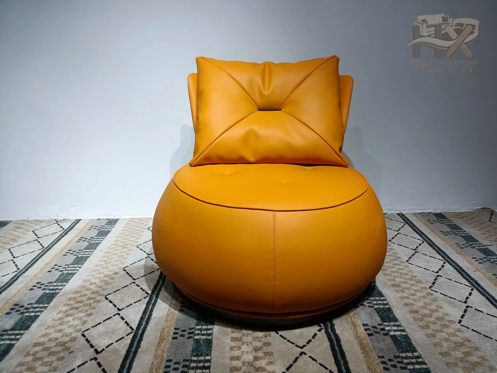 An orange circular base and bowl-like seat support a loose angled back cushion, producing an almost spherical side profile.