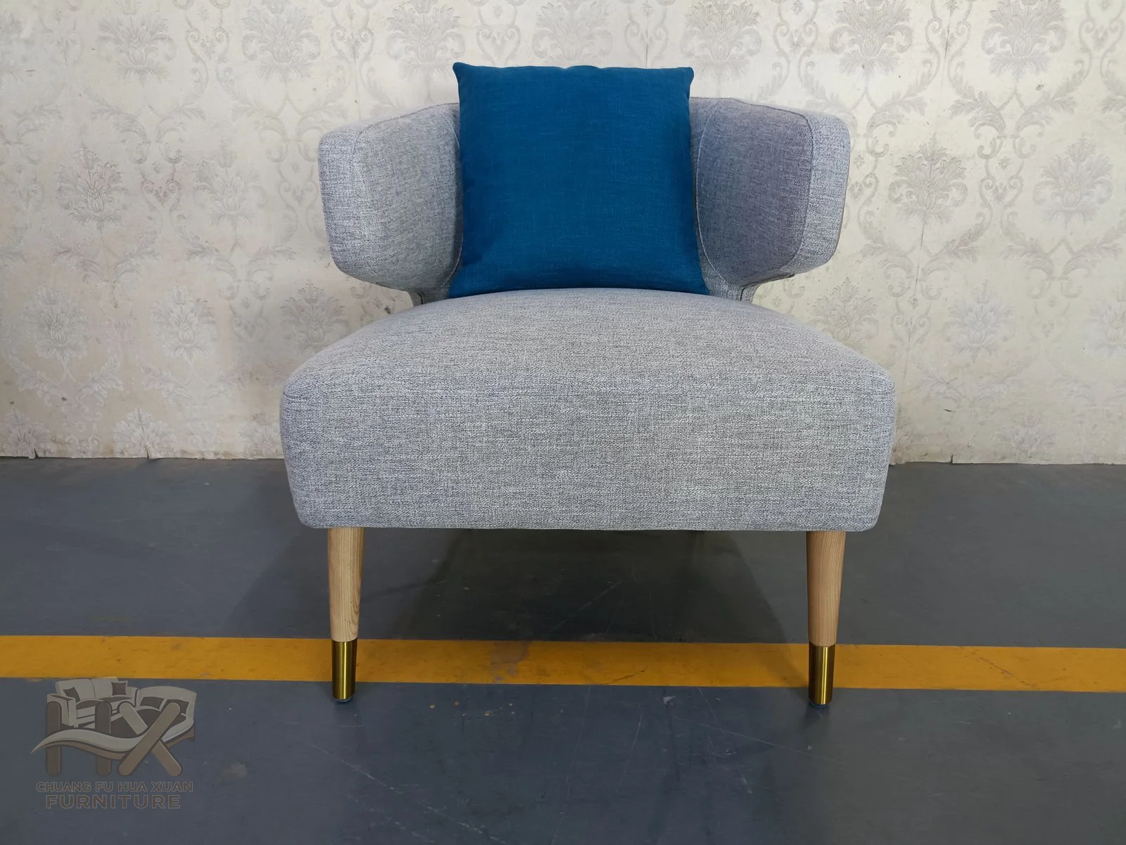 A wide grey seat is accented by a bright blue back cushion and held on narrow tapered legs.