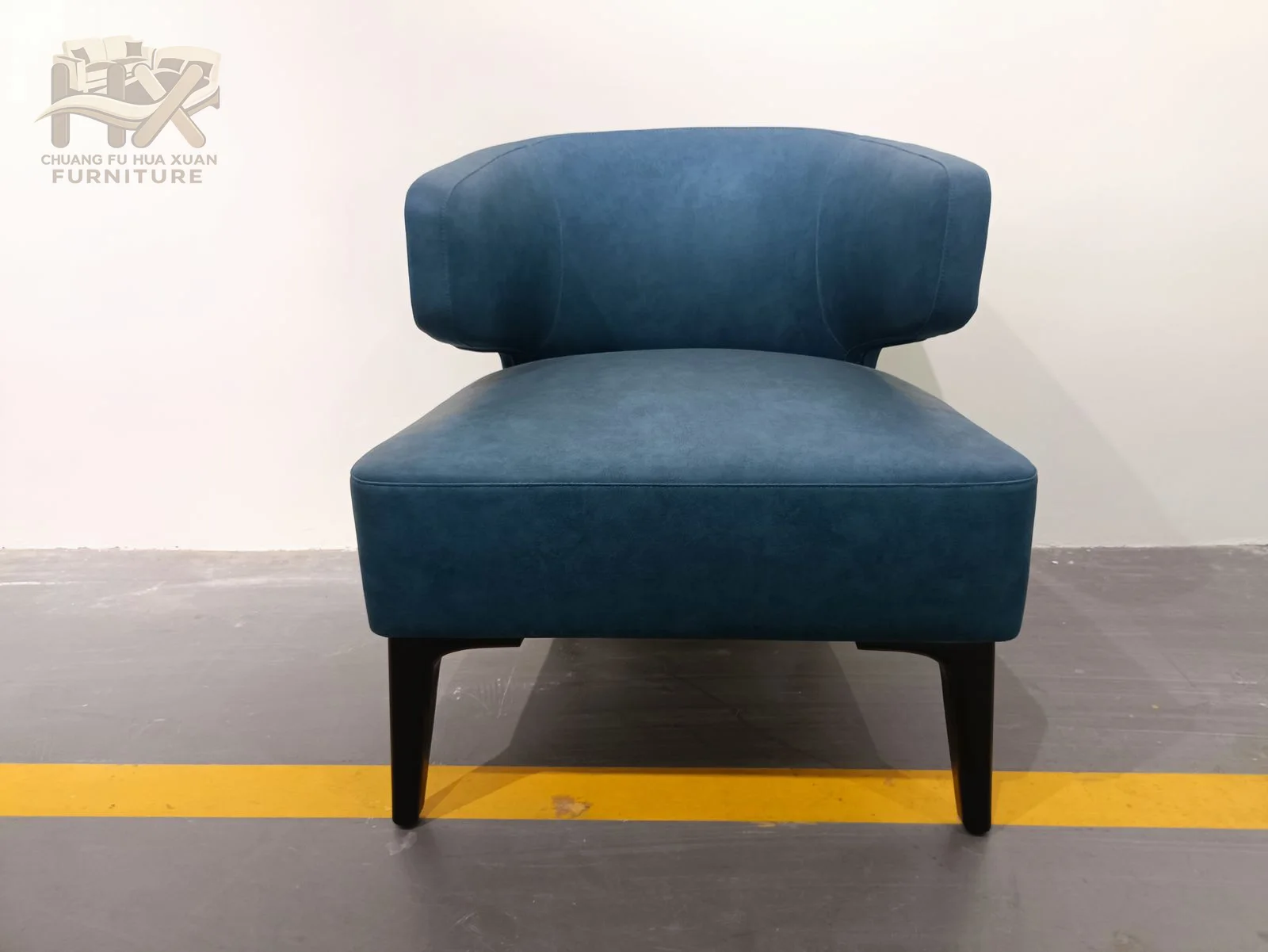 A small separate head cushion lifts above a blue upholstered back and seat on slim dark legs.