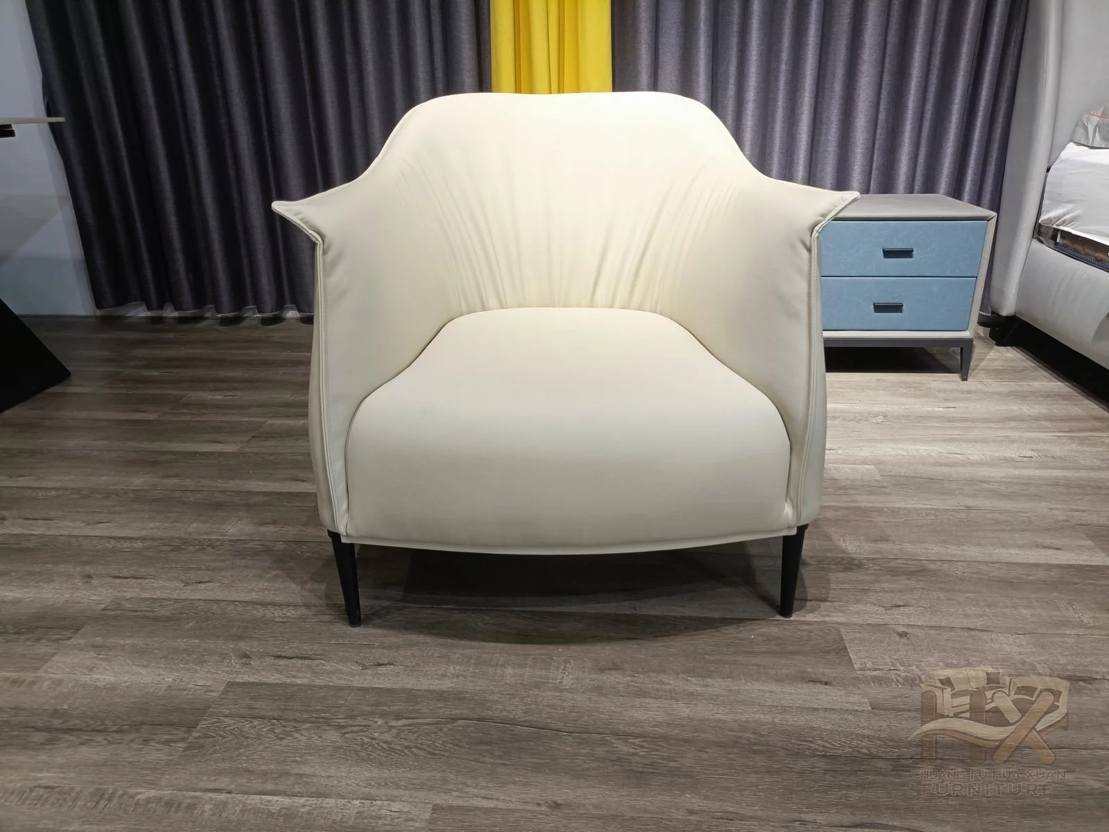 A generous white upholstered shell curves upward behind a low seat, with small dark feet barely visible below.