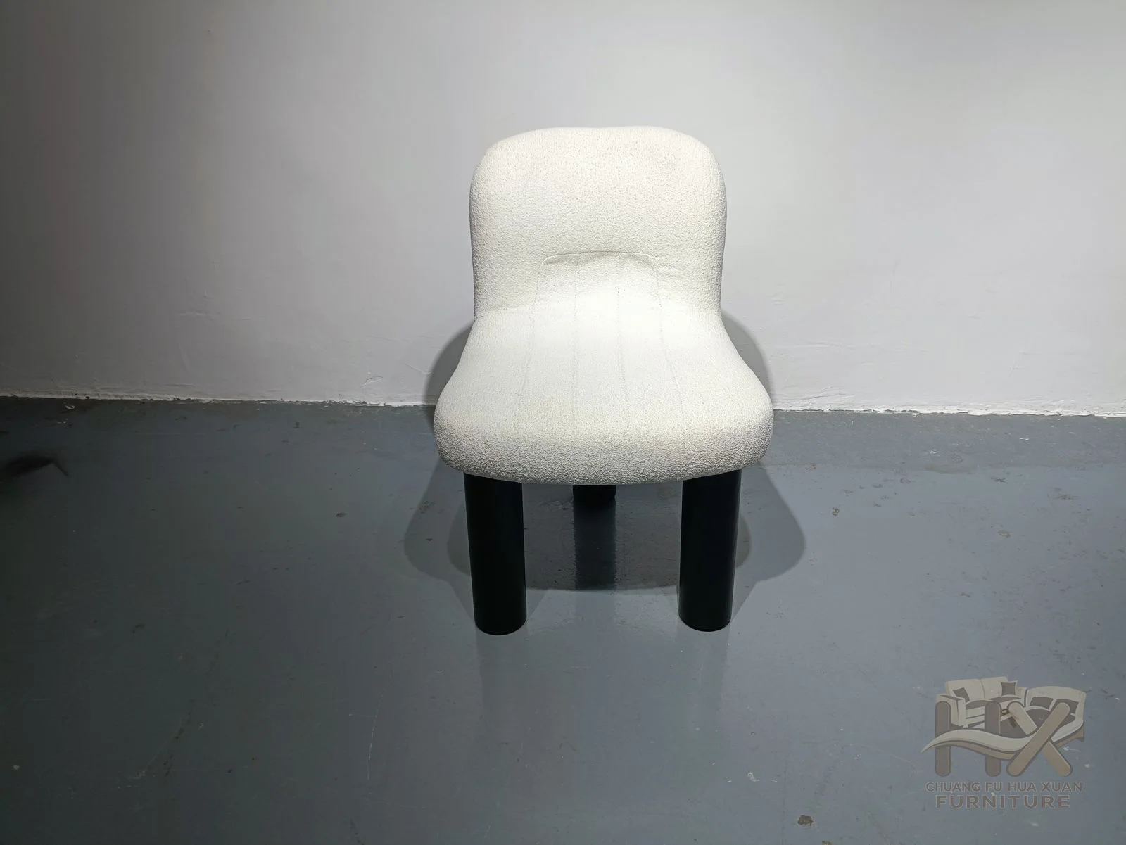 A small white seat is enclosed by rounded upholstered arms and back above short dark feet.