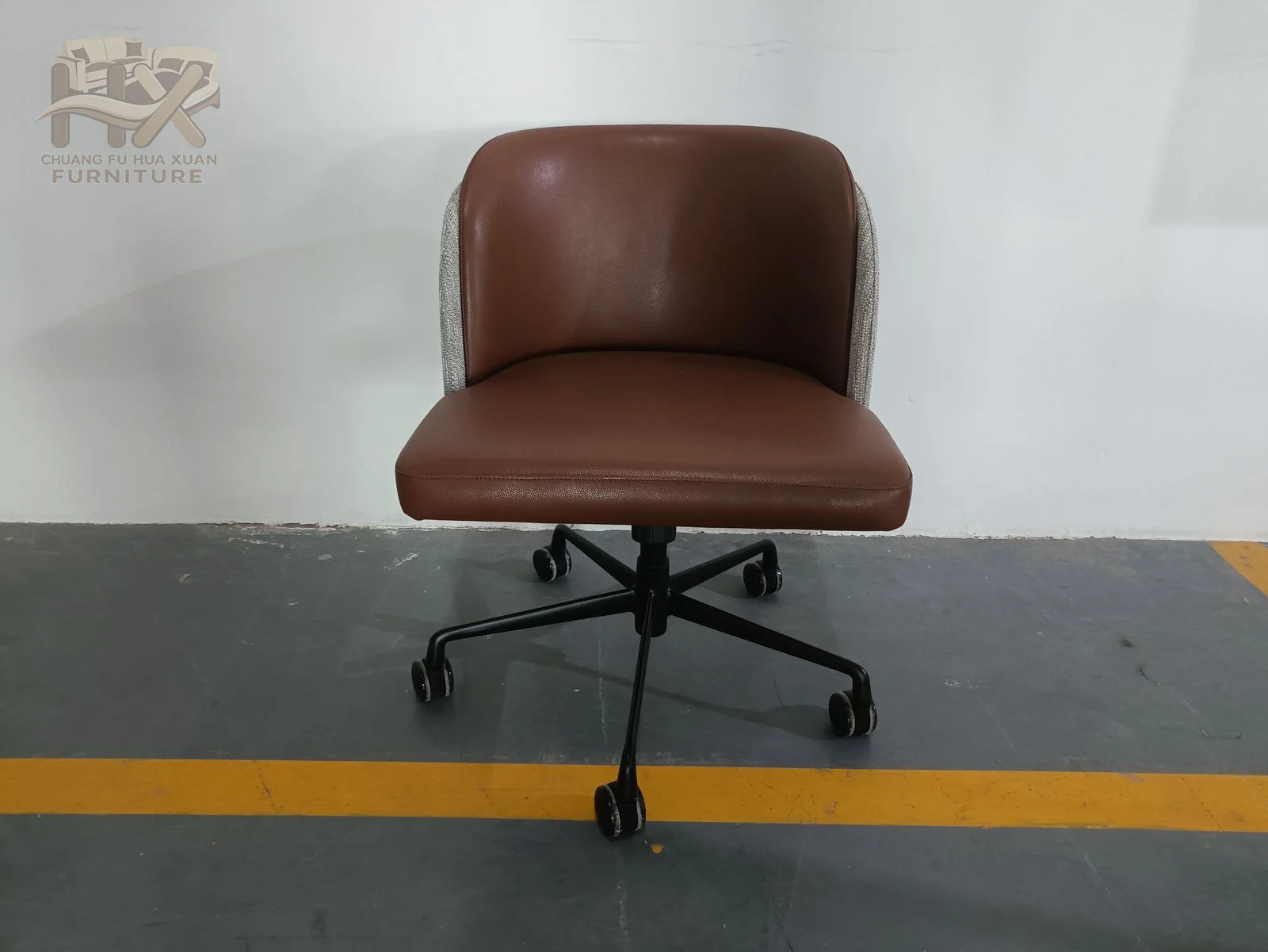 A warm brown upholstered seat and short back sit on a black wheeled swivel base.