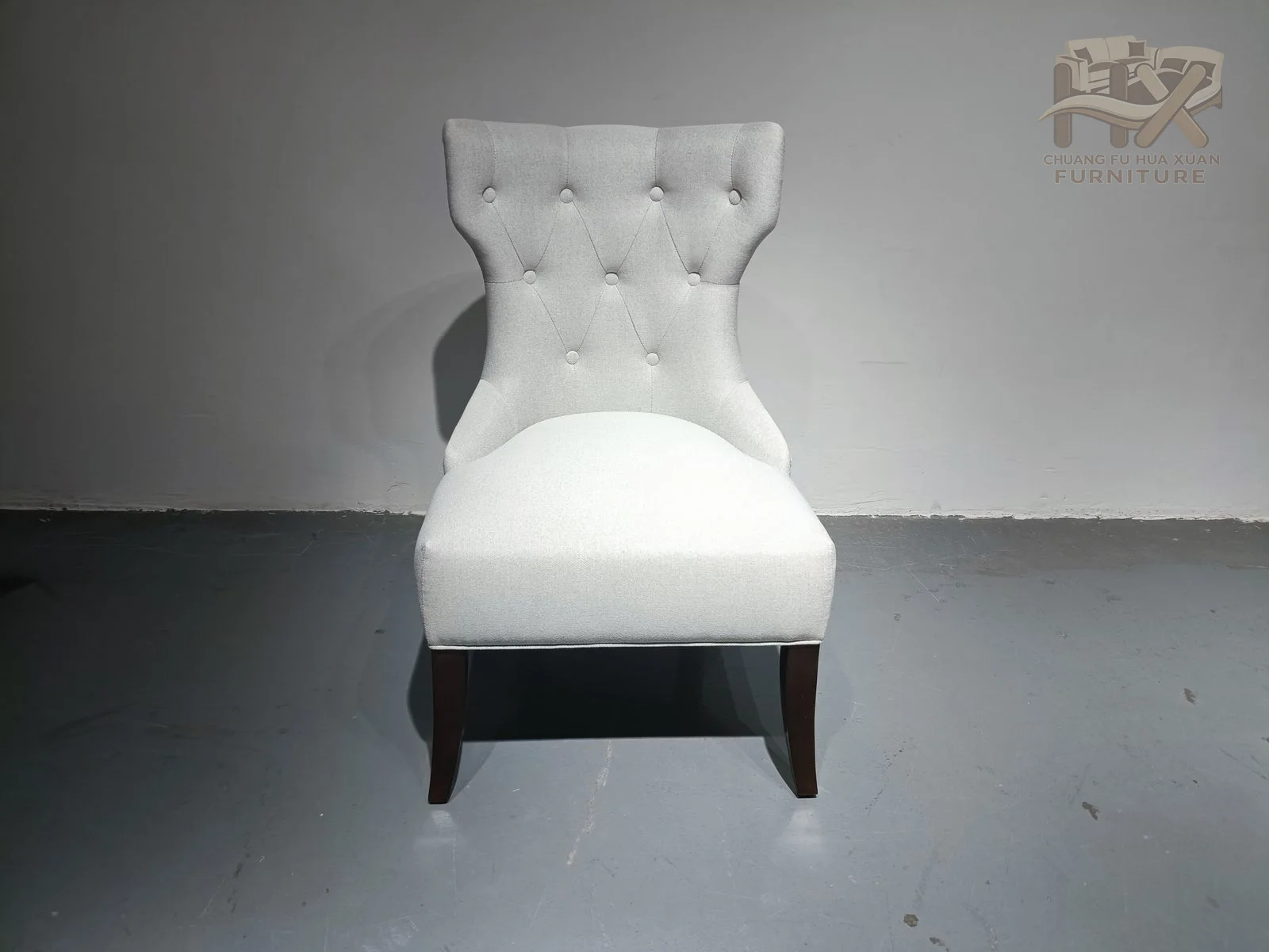 A high white back gathers into soft tufting above a compact seat and short dark feet.