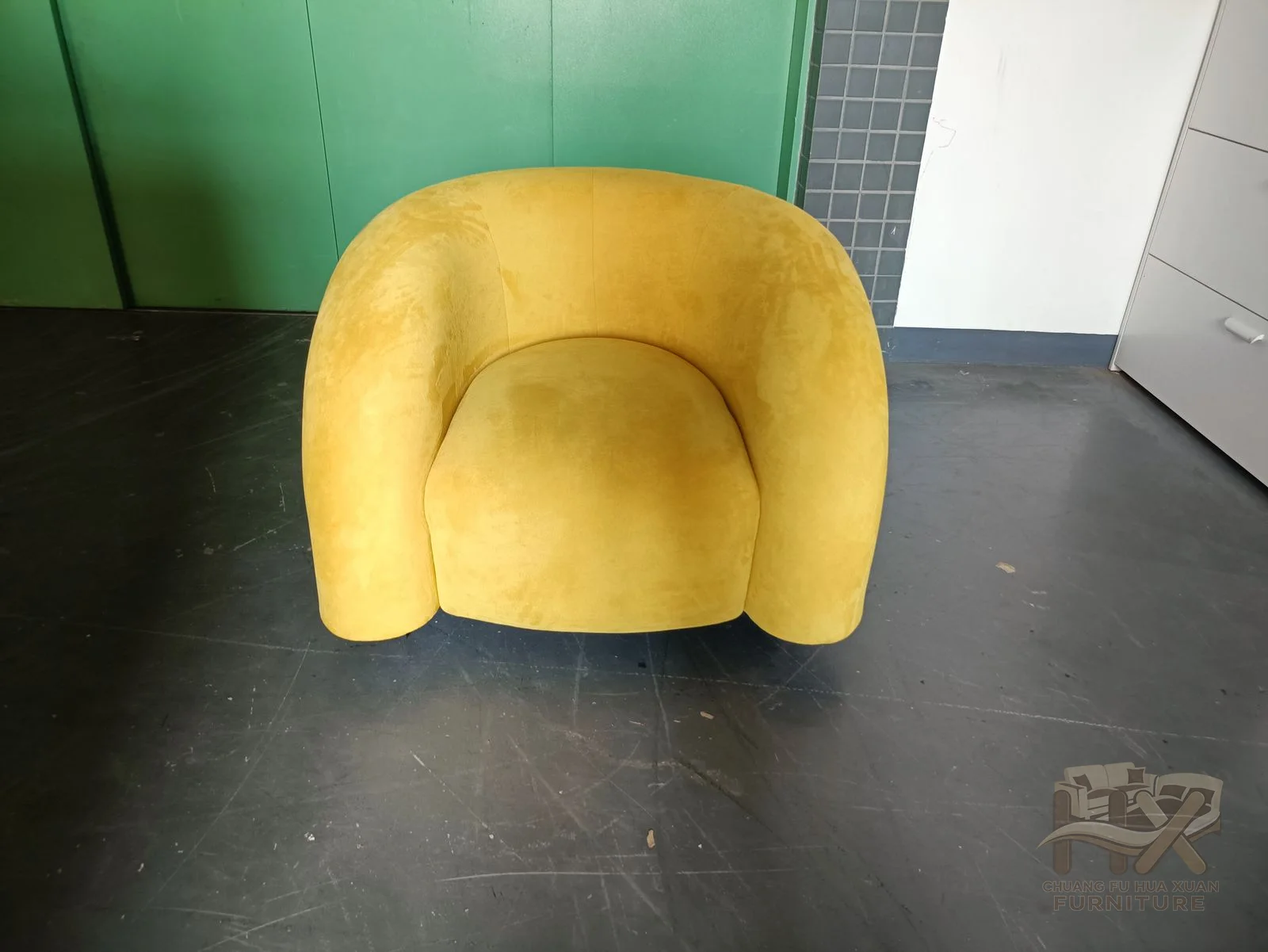 A vivid yellow upholstered shell folds into rounded arms around a low compact seat.