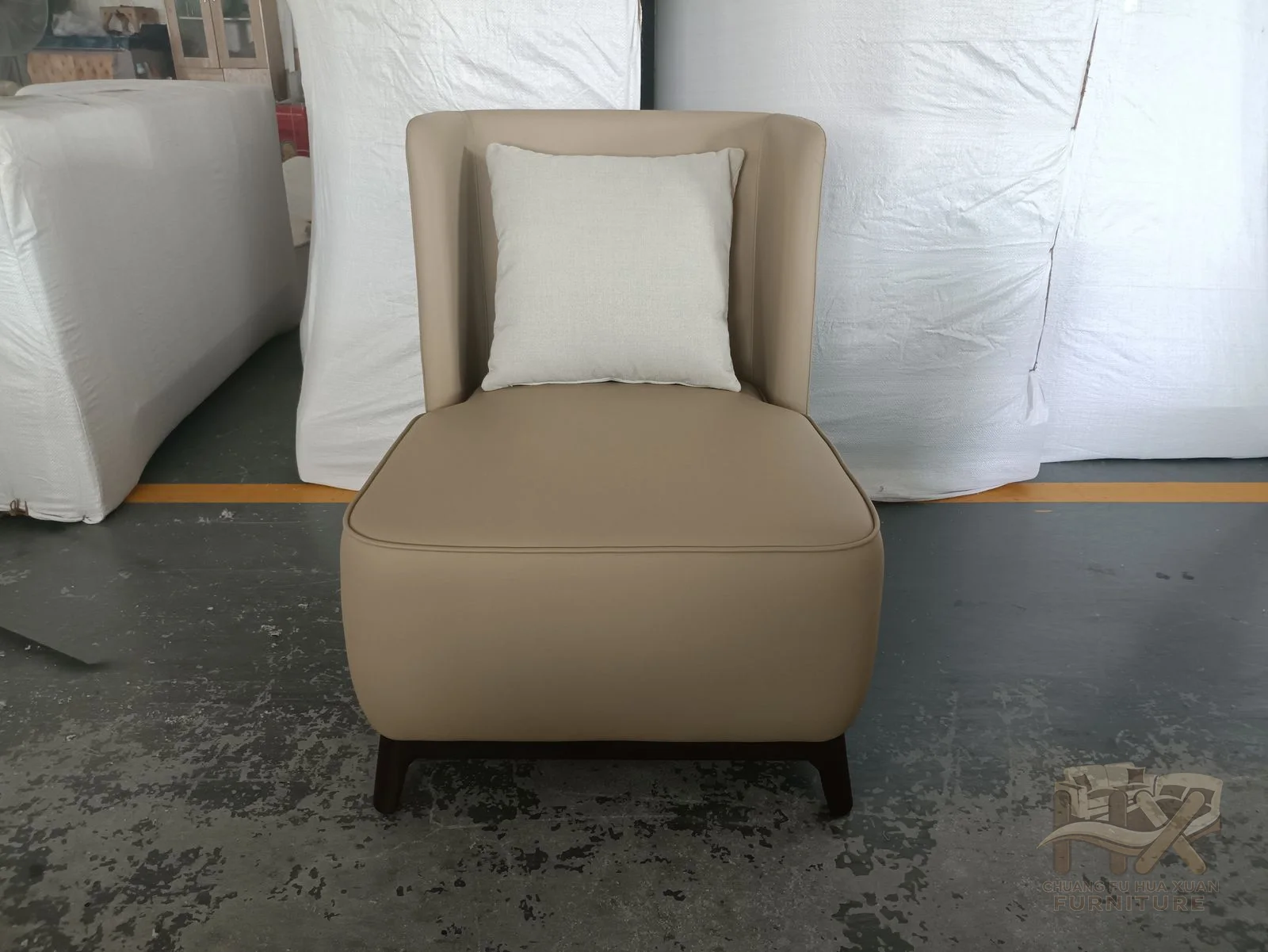 A beige chair has a deep seat cushion within short straight arms and a softly curved back.