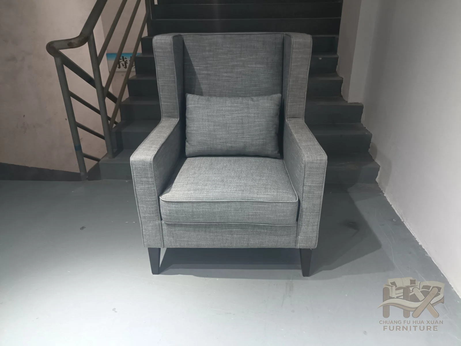 A tall grey chair encloses a thick seat cushion between padded arms, shown in smooth and textured covers.