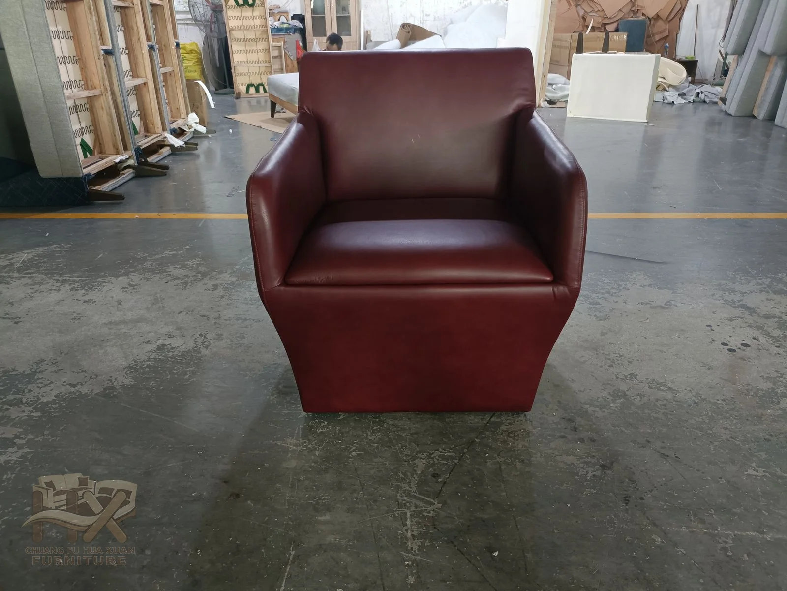 A burgundy chair uses broad square arms and a low upholstered base around one deep seat cushion.