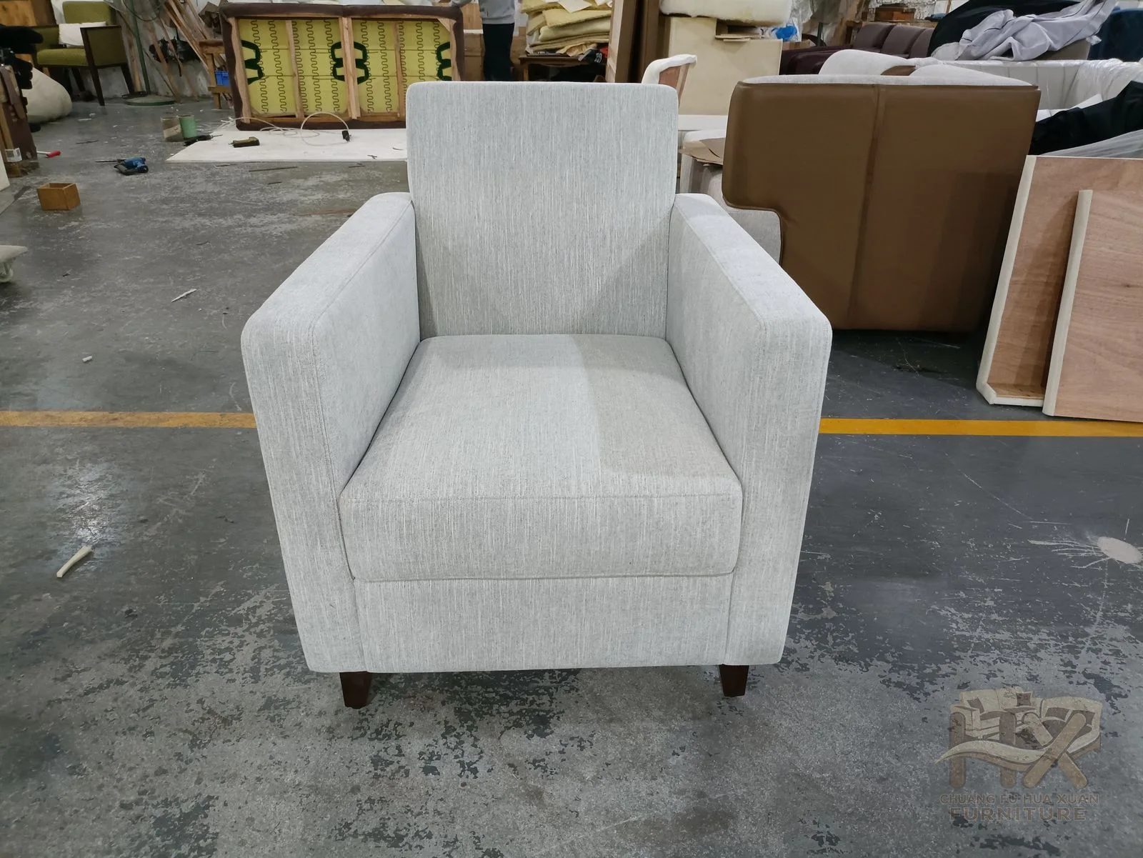 A white seat is framed by sharply angled arms and a high upright back above low dark feet.