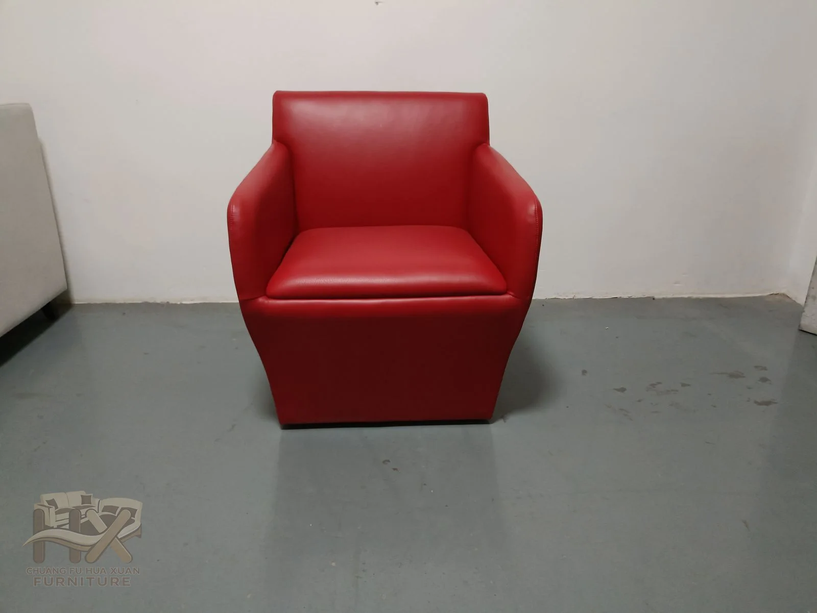 A bright red back and seat sit between upright square arms over a low dark base.