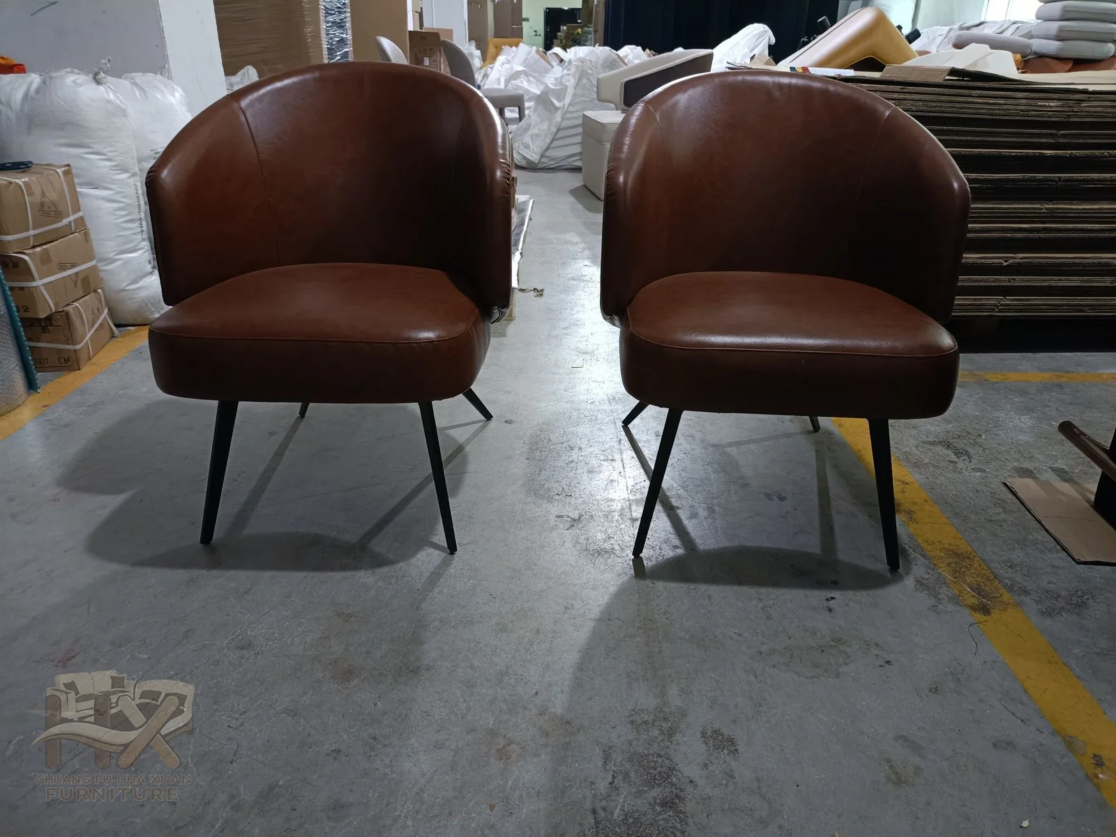 A chocolate-brown compact chair wraps its low arms into a curved back above a small dark base.