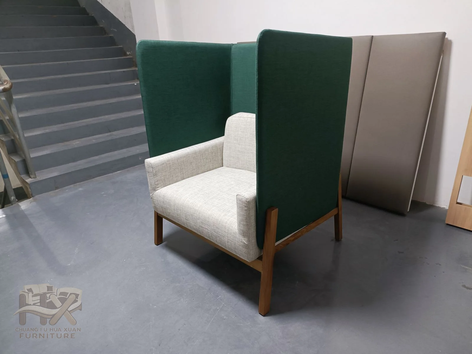 A deep green club chair curves its short arms into a compact cushioned back.