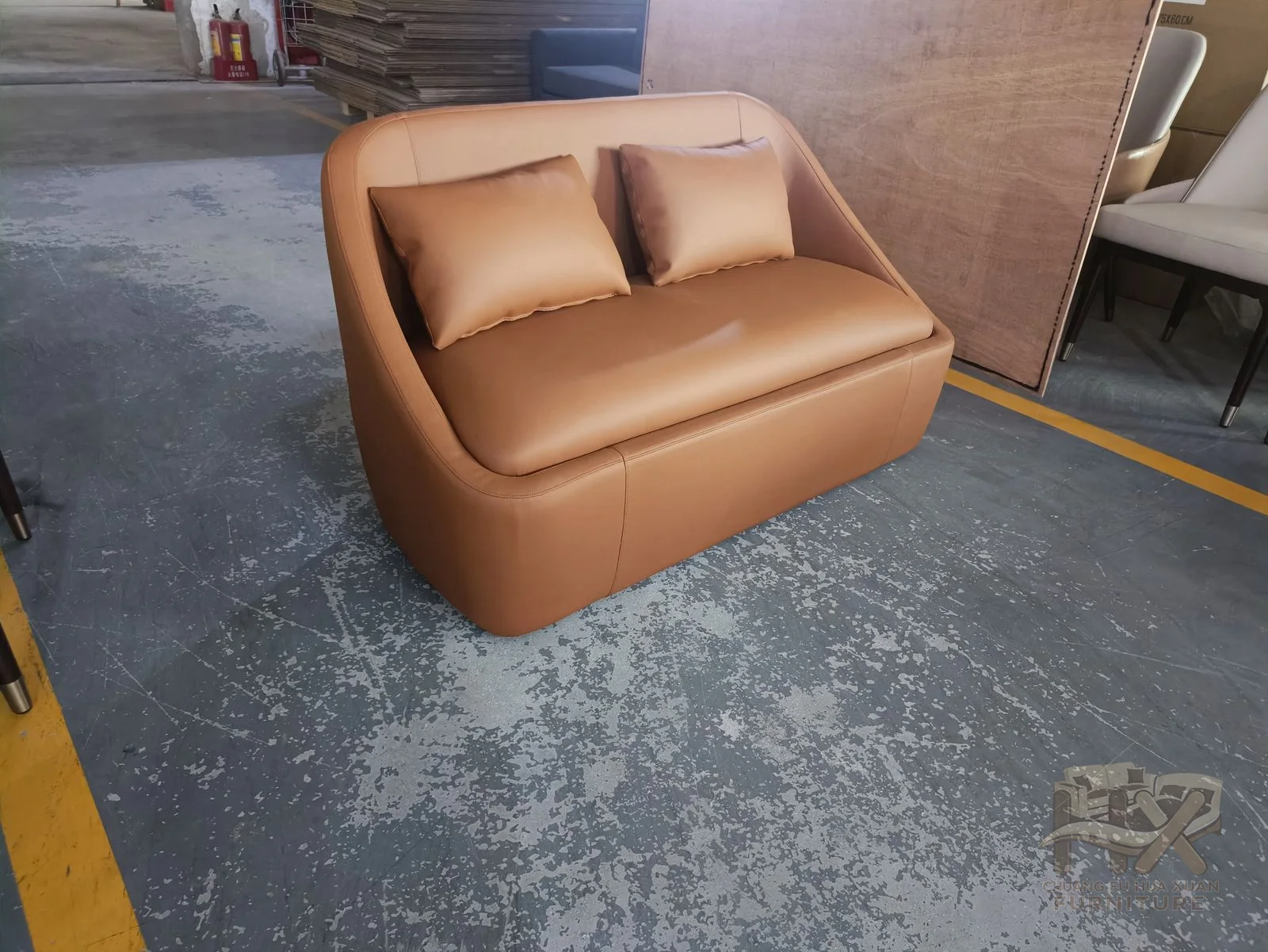 A warm brown chair has one broad seat inside a rounded upholstered back and arms.