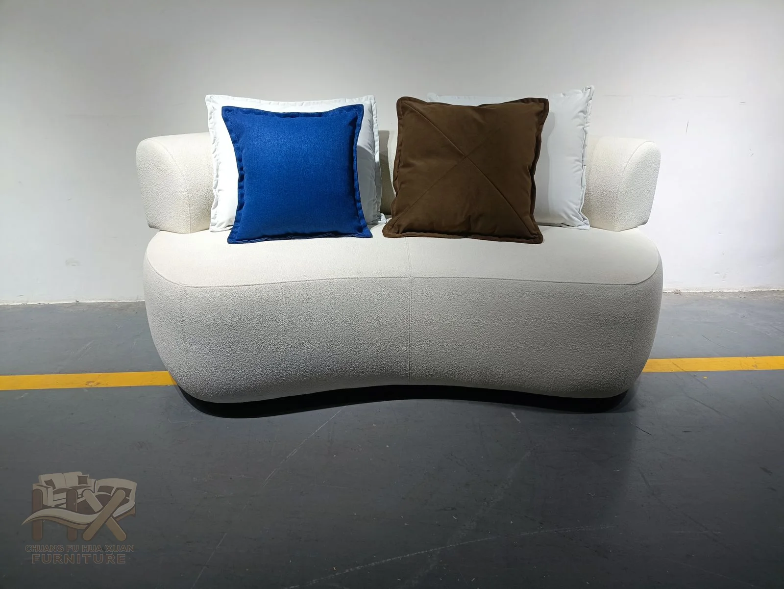 A white lounge chair lifts a gently curved back above a broad single seat and low arms.
