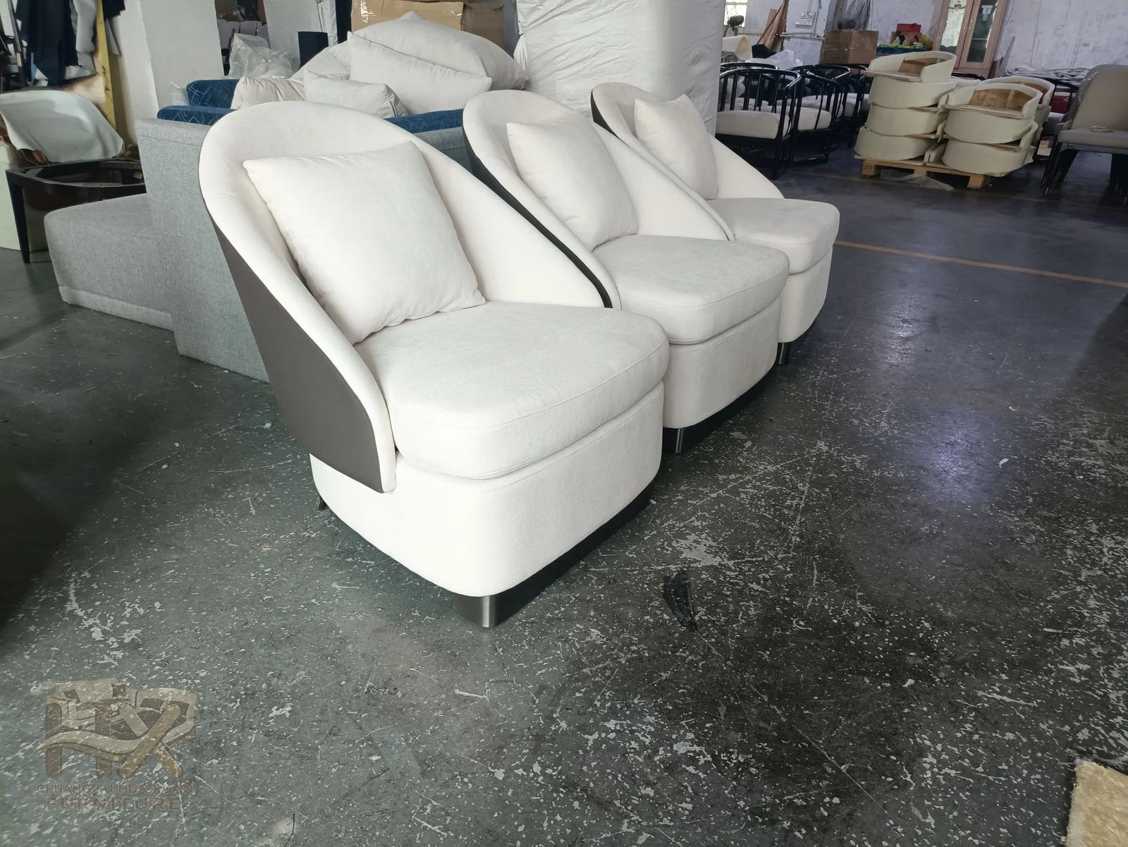 A white tub-shaped chair wraps a low back around one seat above a concealed swivel base.