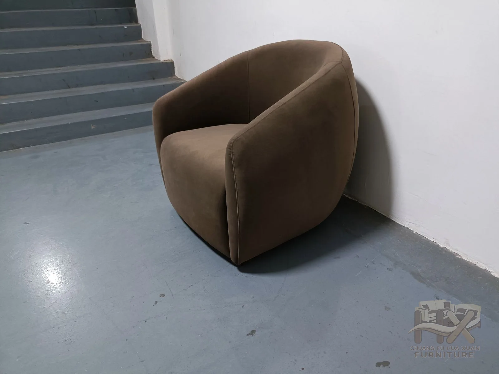 A brown tub chair curves a padded back into short arms above a hidden base.
