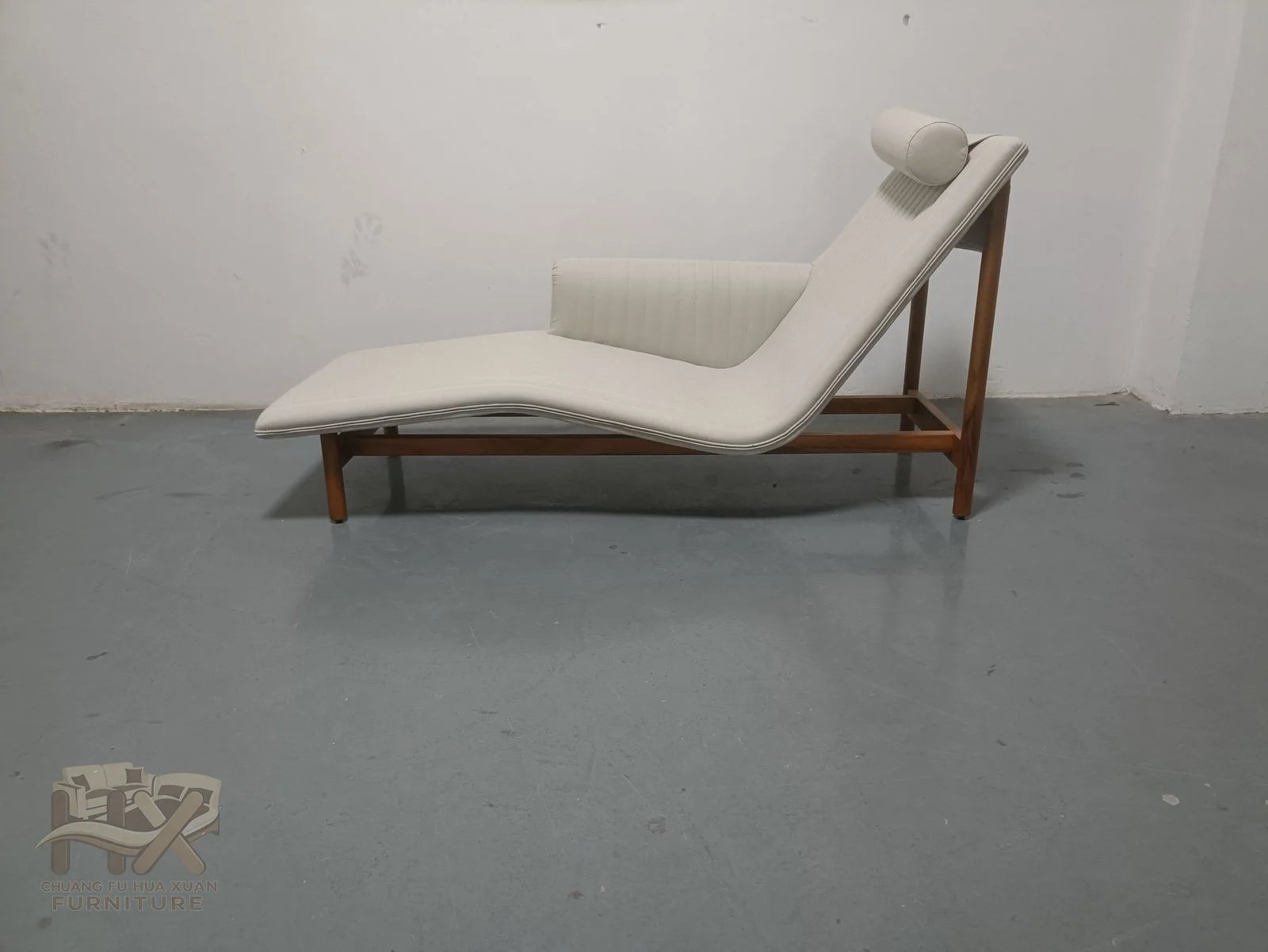 A pale chaise lengthens into a reclining seat with a raised back at one end.