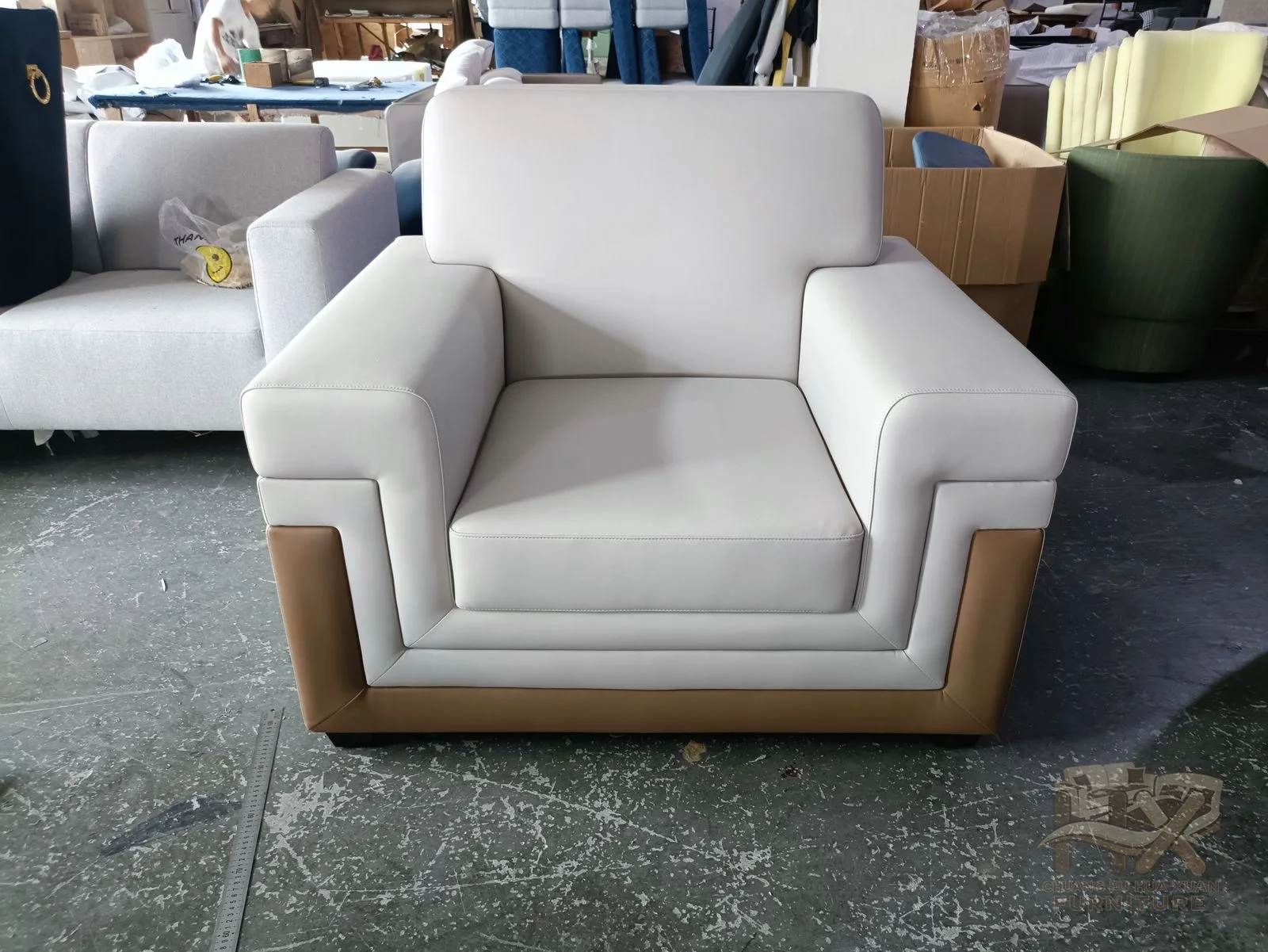 A white compact armchair has short upright arms, a padded back and a single deep cushion.