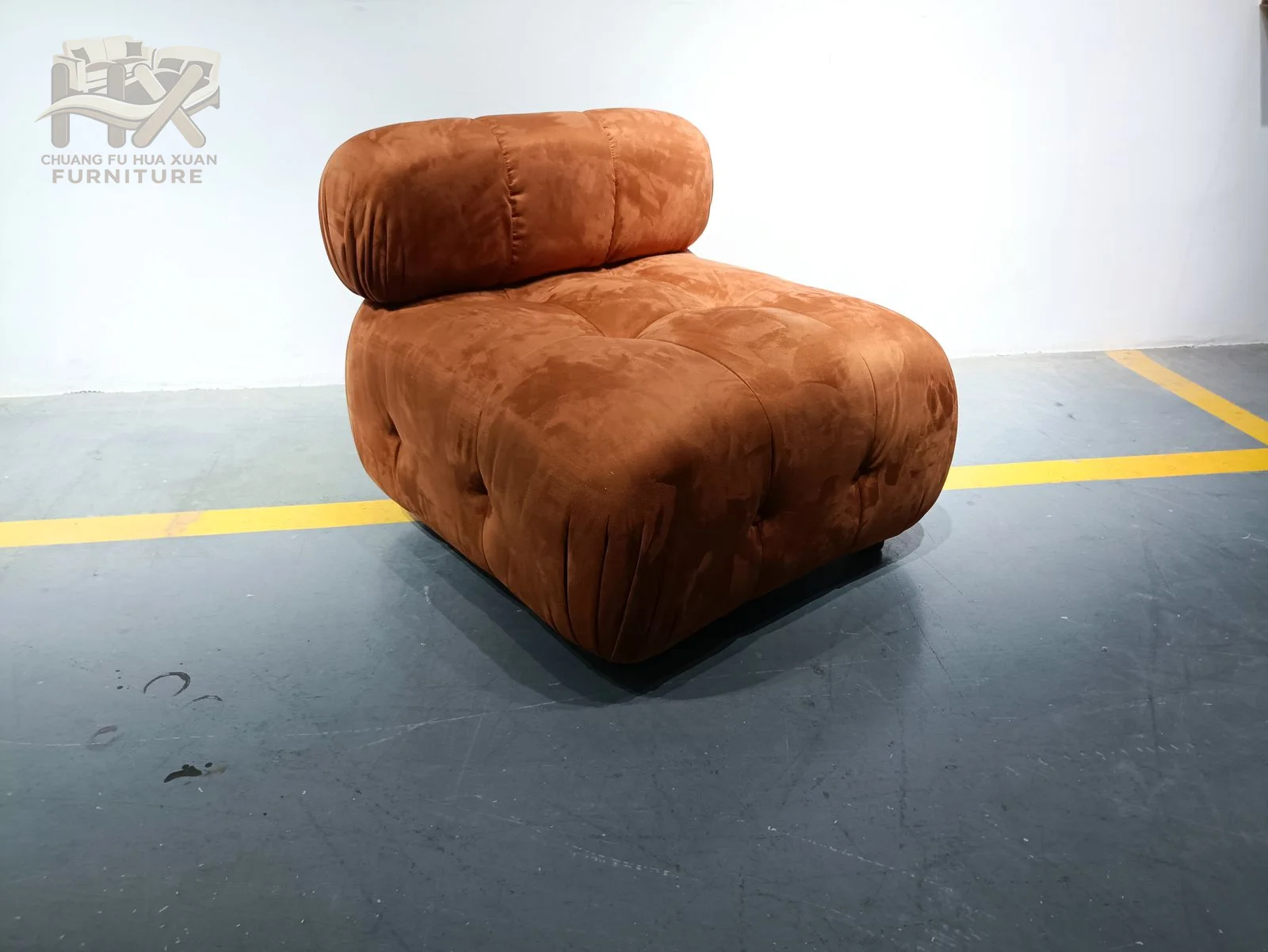 A rust upholstered lounge chair has a broad armless seat and a gently sloping back.