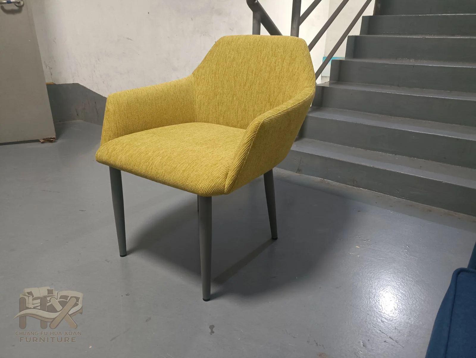 A yellow upholstered seat sits inside short open arms on slim dark legs.
