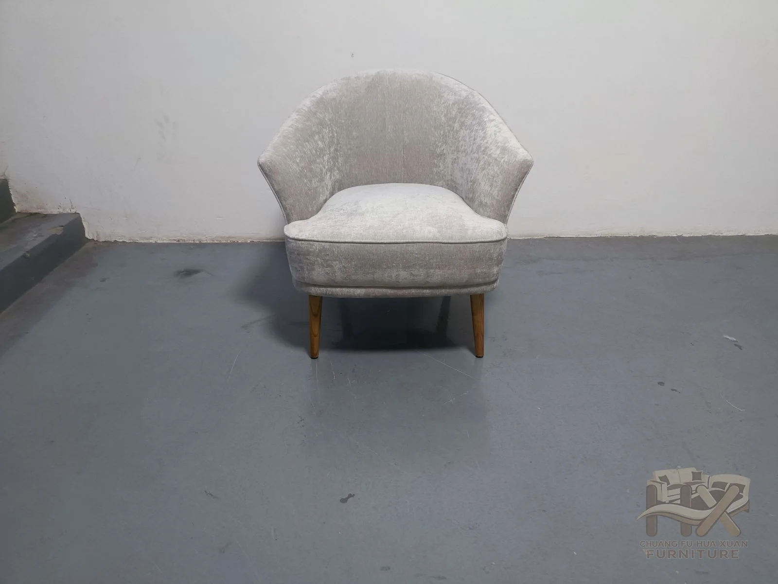 A pale chair combines a slim inclined back with a broad seat and compact arms.