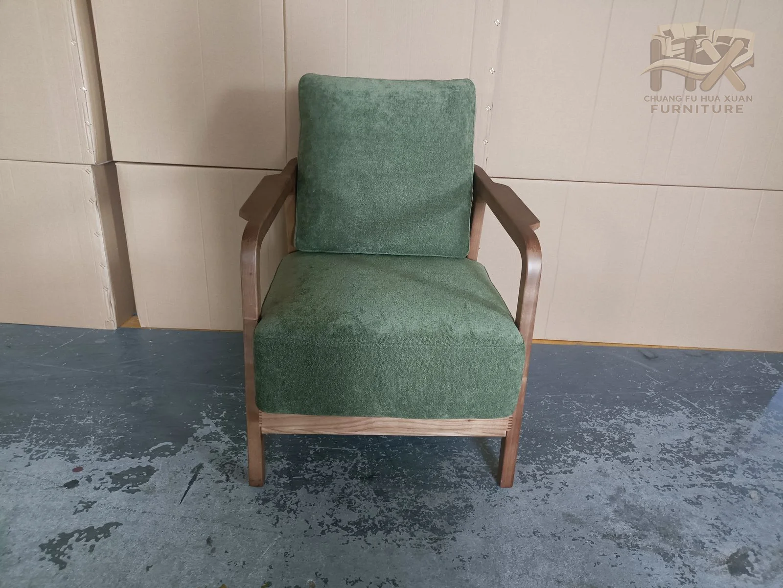 Green upholstered cushions sit inside an exposed warm wood-look arm and leg frame.