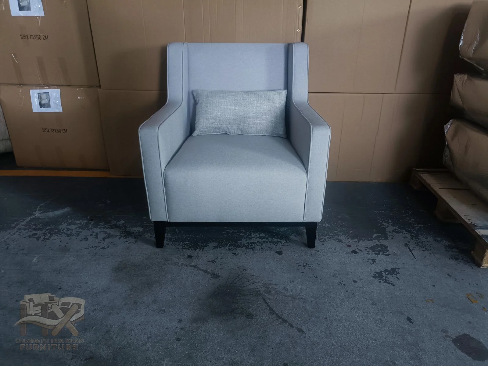 A pale armchair has upright square arms and a single deep seat against a high back.