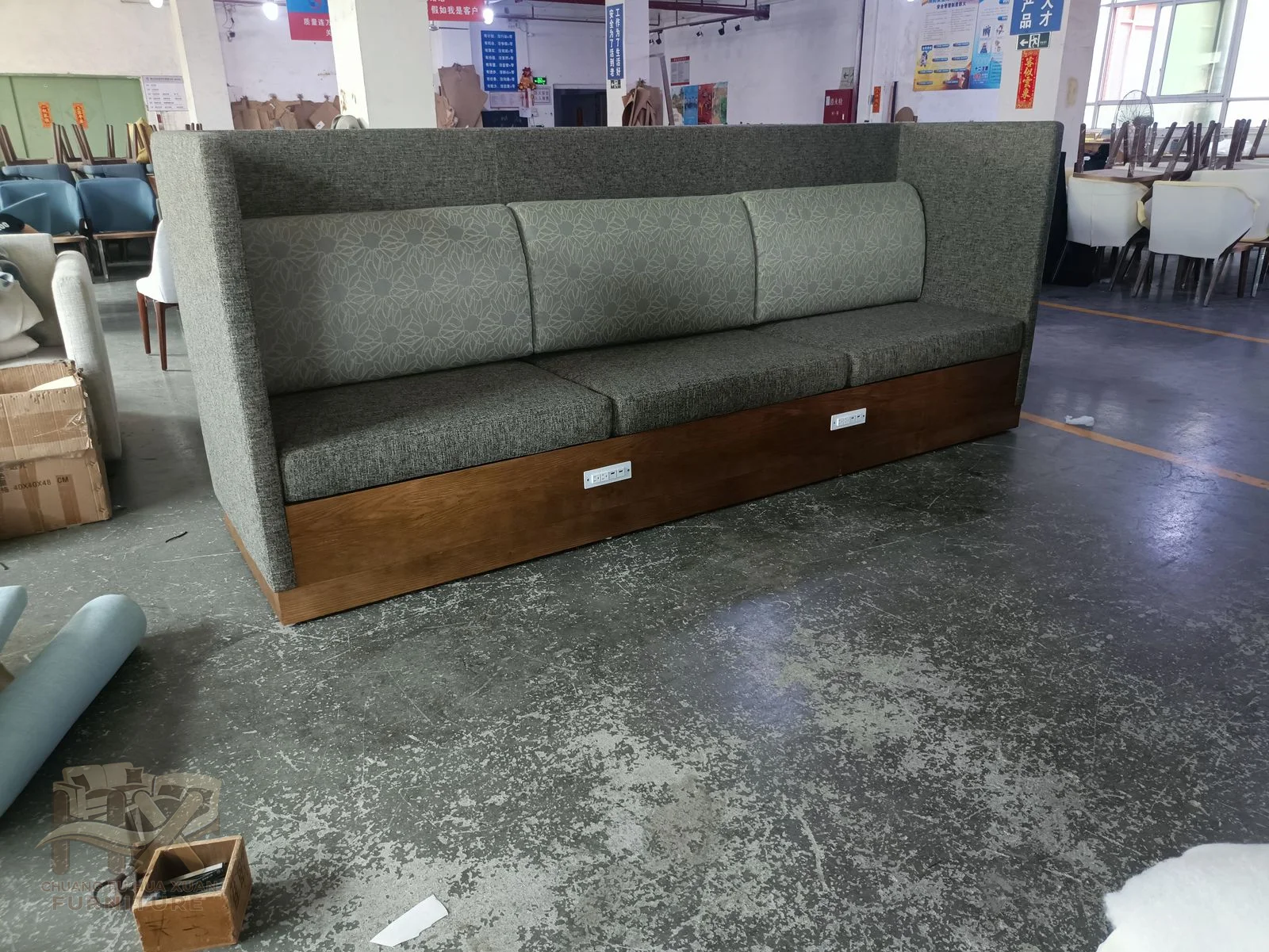 A long green banquette has a straight padded back and seat above a visible wood-look base.