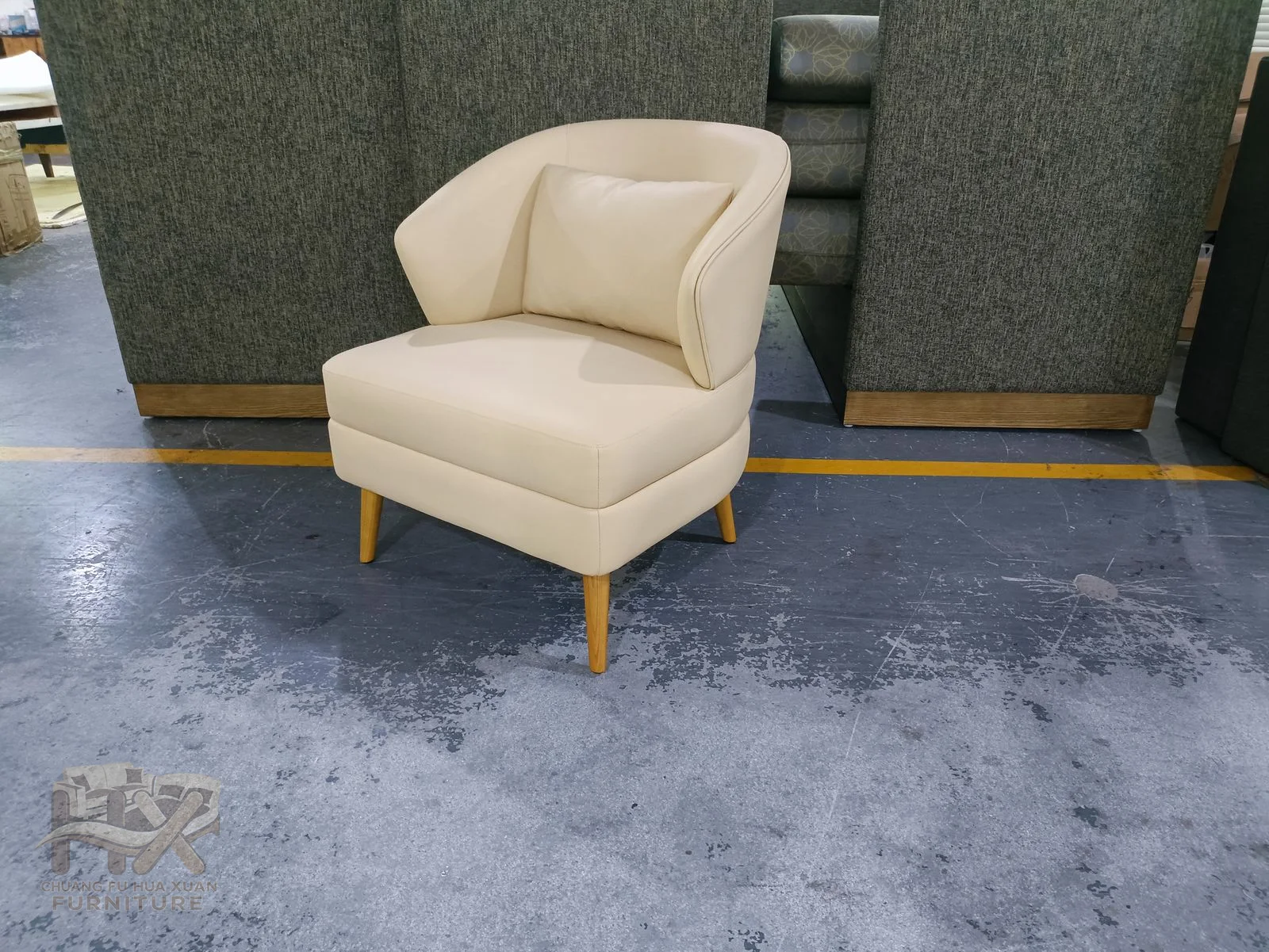 A cream lounge chair has a tall rounded back and broad individual seat on a low base.