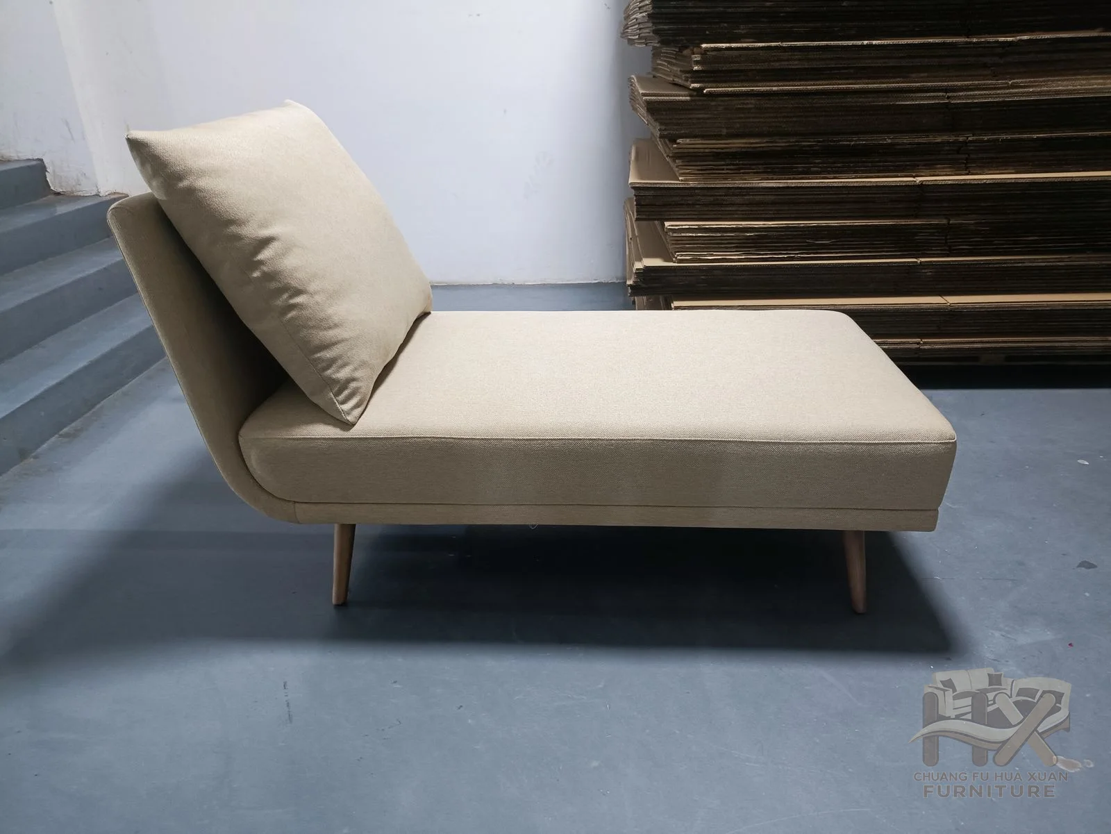 An ivory chaise has a long flat seat and raised pillow back with no projecting arms.