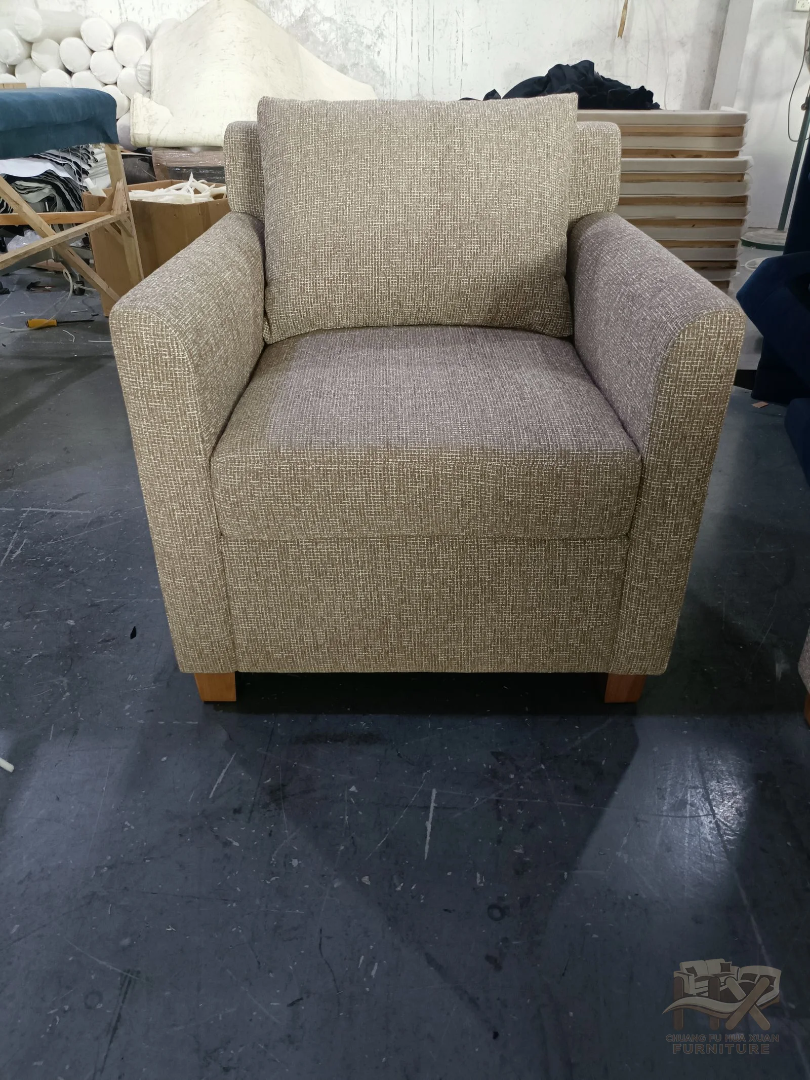 A taupe chair has a high rounded back above a single deep seat and short arms.