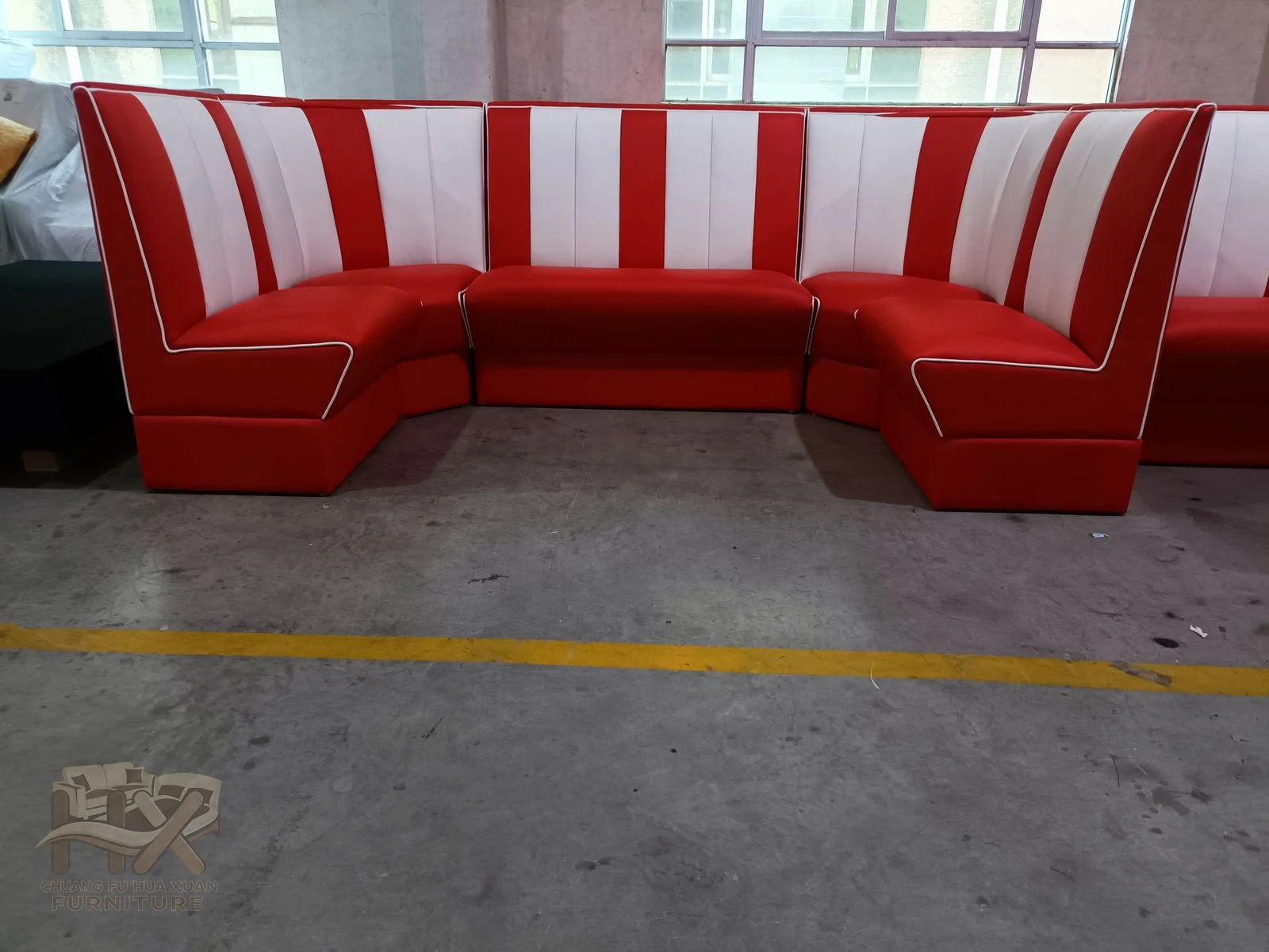 A curved red restaurant banquette repeats broad white vertical panels across its back.
