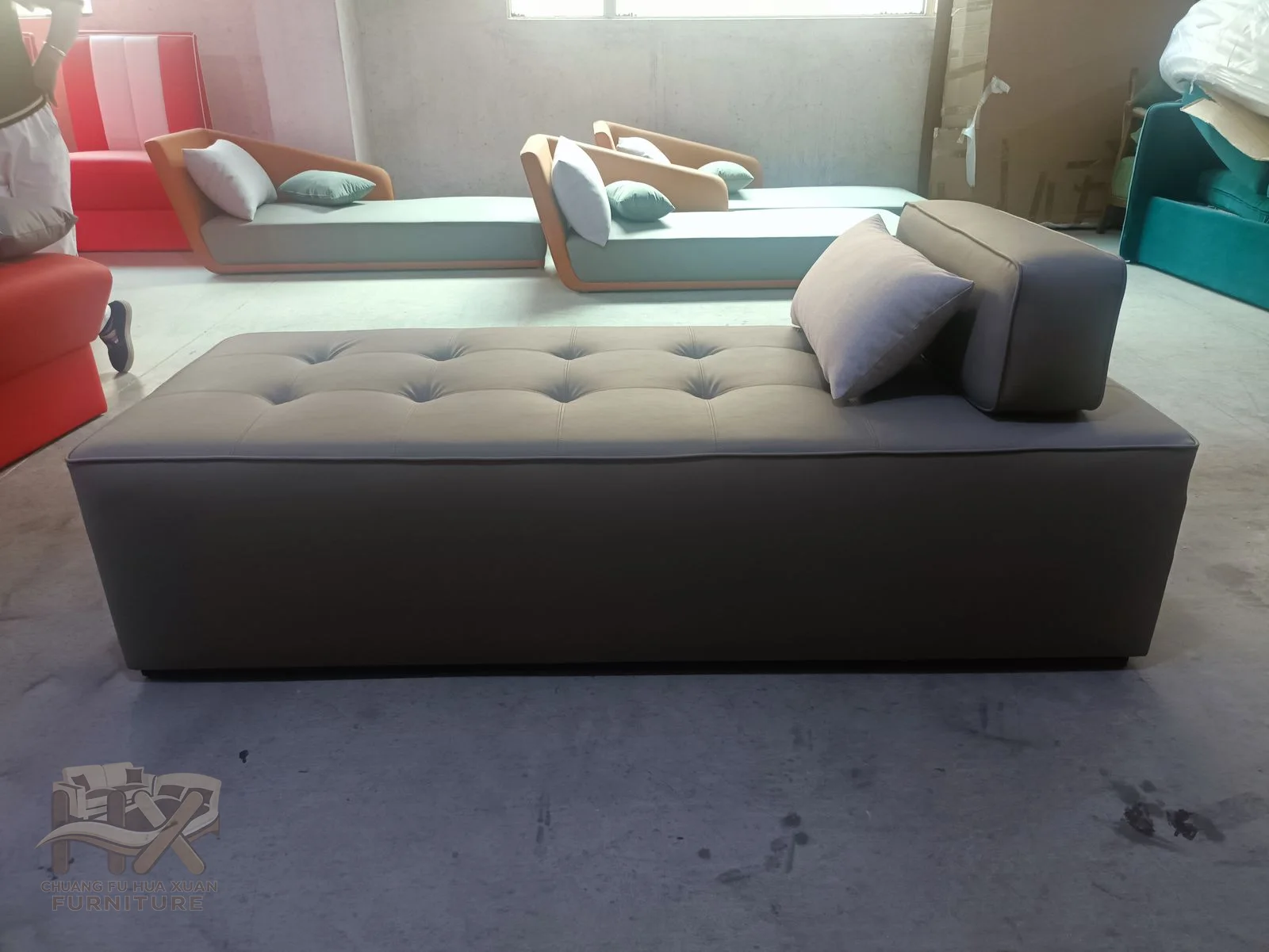 A taupe chaise extends a button-tufted reclining surface from a raised back.