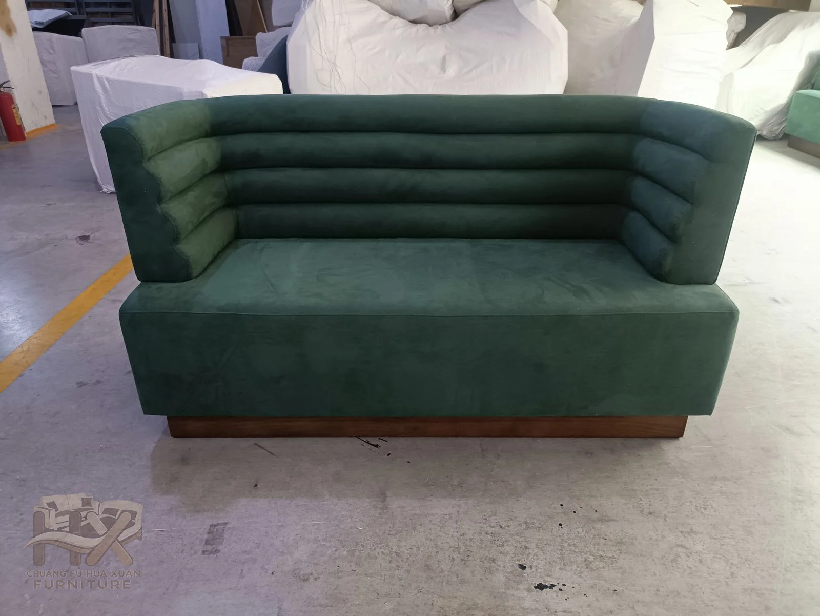 A green booth banquette has a horizontally ribbed back and compact continuous seat.