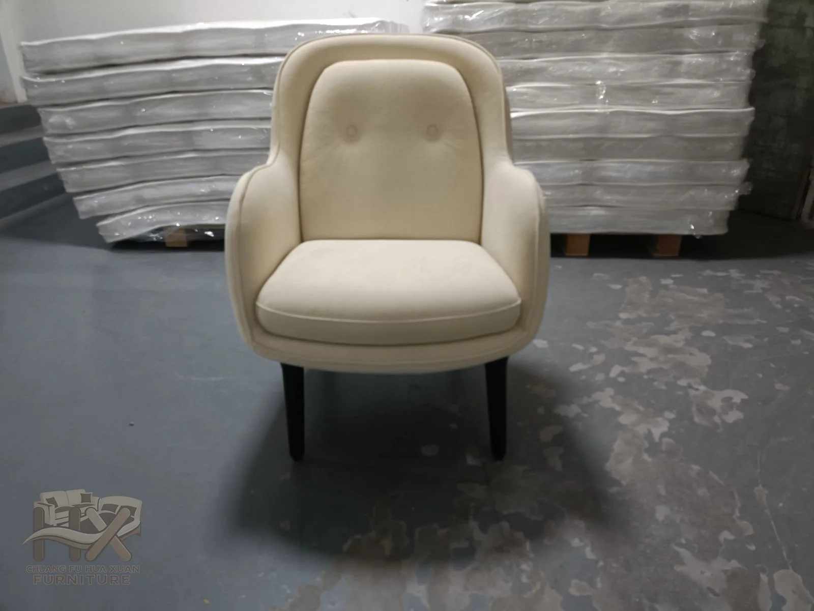 An ivory chair rounds its arms and back around a deep seat on a concealed turning base.